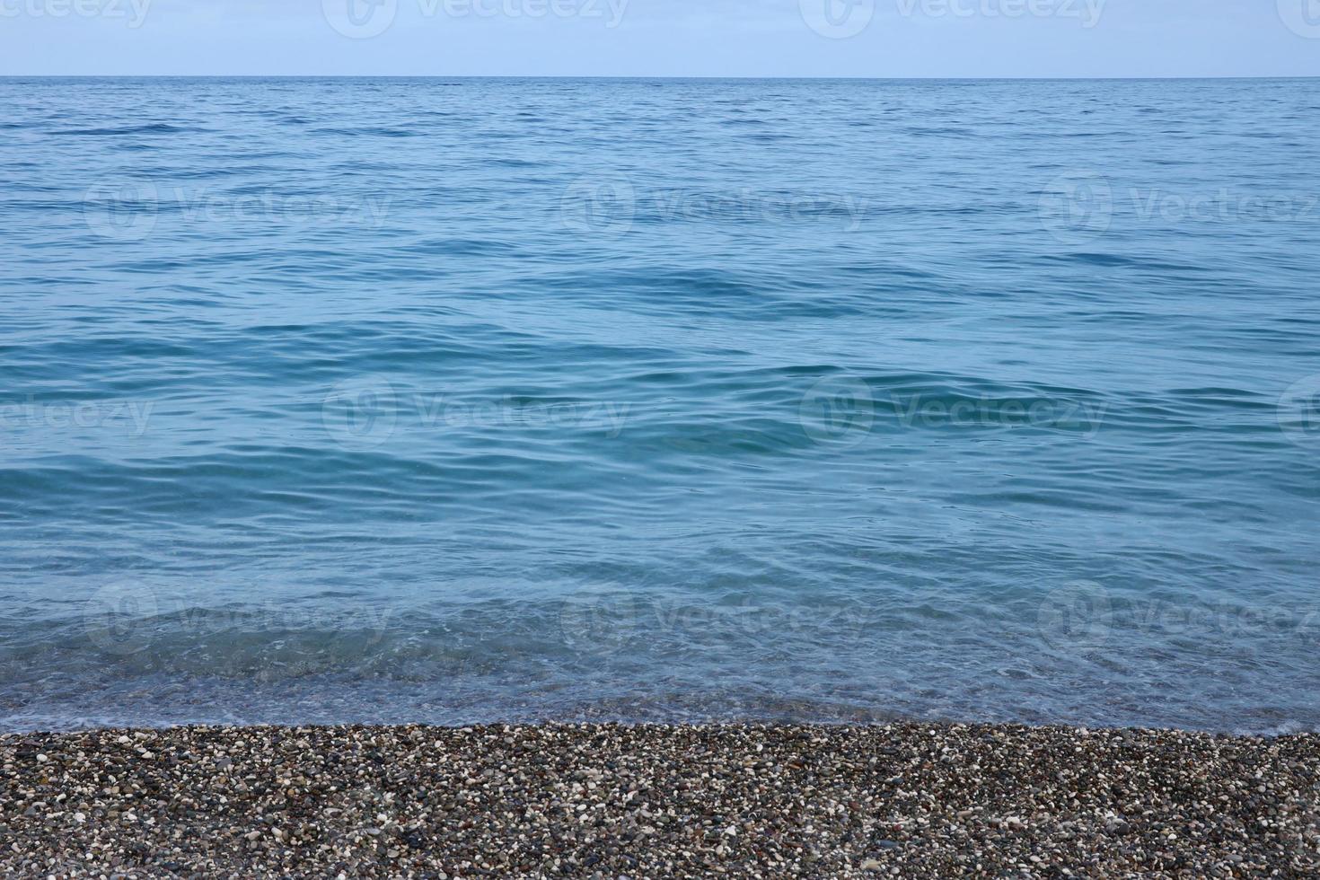 banco de guijarros con el mar y la playa al fondo foto
