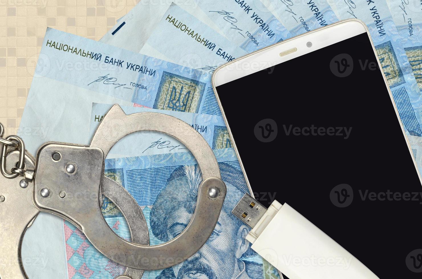 5 Ukrainian hryvnias bills and smartphone with police handcuffs. Concept of hackers phishing attacks, illegal scam or malware soft distribution photo