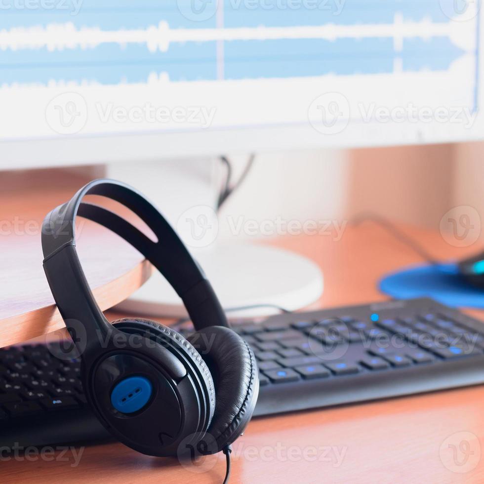 Big black headphones lie on the wooden desktop of the sound designer photo