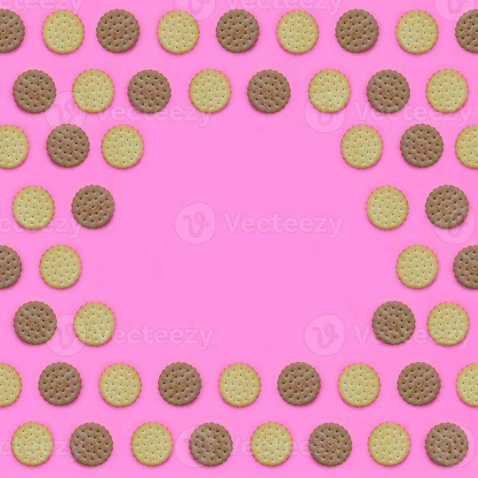 Frame of a brown biscuits on a pink background. Trendy minimal concept of food and dessert. Abstract flat lay, top view photo