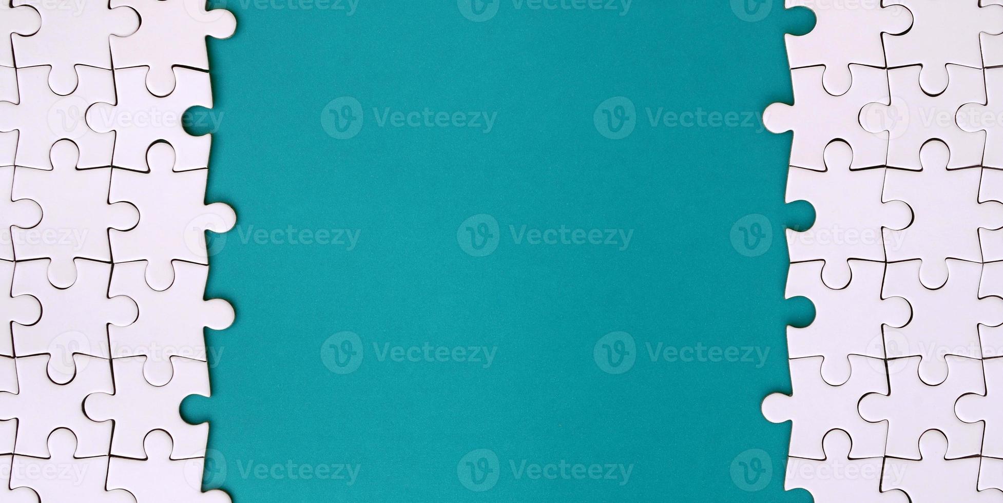 Fragment of a folded white jigsaw puzzle on the background of a blue plastic surface. Texture photo with copy space for text