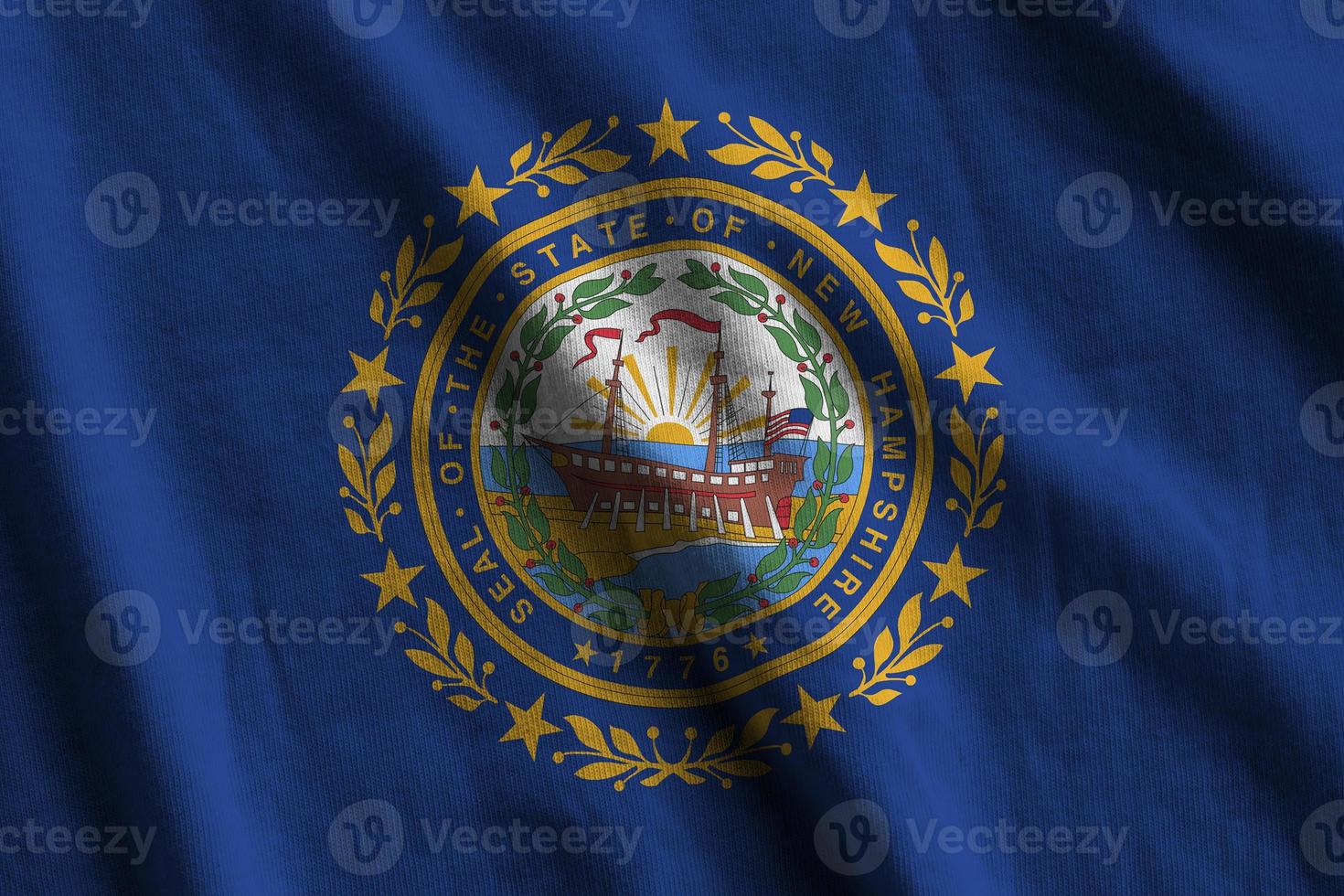 bandera del estado de new hampshire us con grandes pliegues ondeando de cerca bajo la luz del estudio en el interior. los símbolos y colores oficiales en banner foto