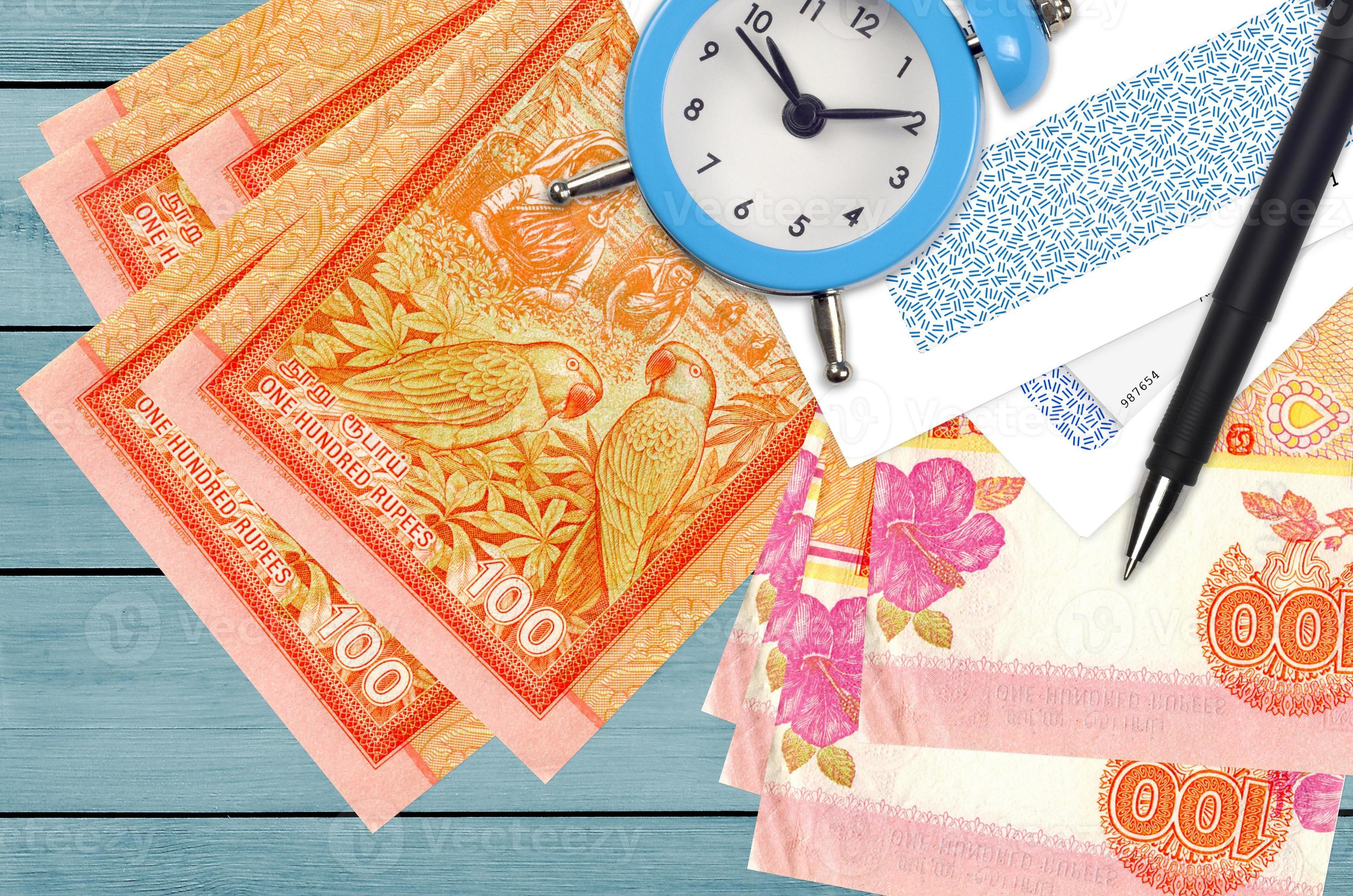 100 Sri Lankan rupees bills and alarm clock with pen and envelopes. Tax