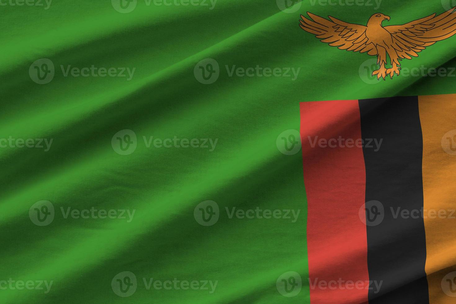 Zambia flag with big folds waving close up under the studio light indoors. The official symbols and colors in banner photo