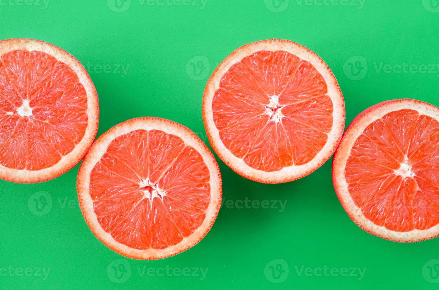 Top view of a several grapefruit slices on bright background in green color. A saturated citrus texture image photo
