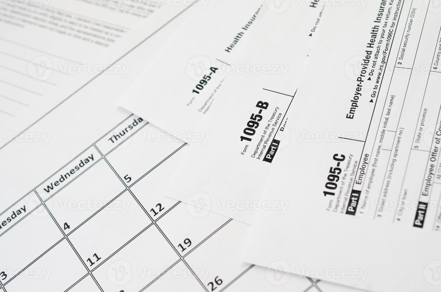 IRS Form 1095-A 1095-B and 1095-C blank lies on empty calendar page photo
