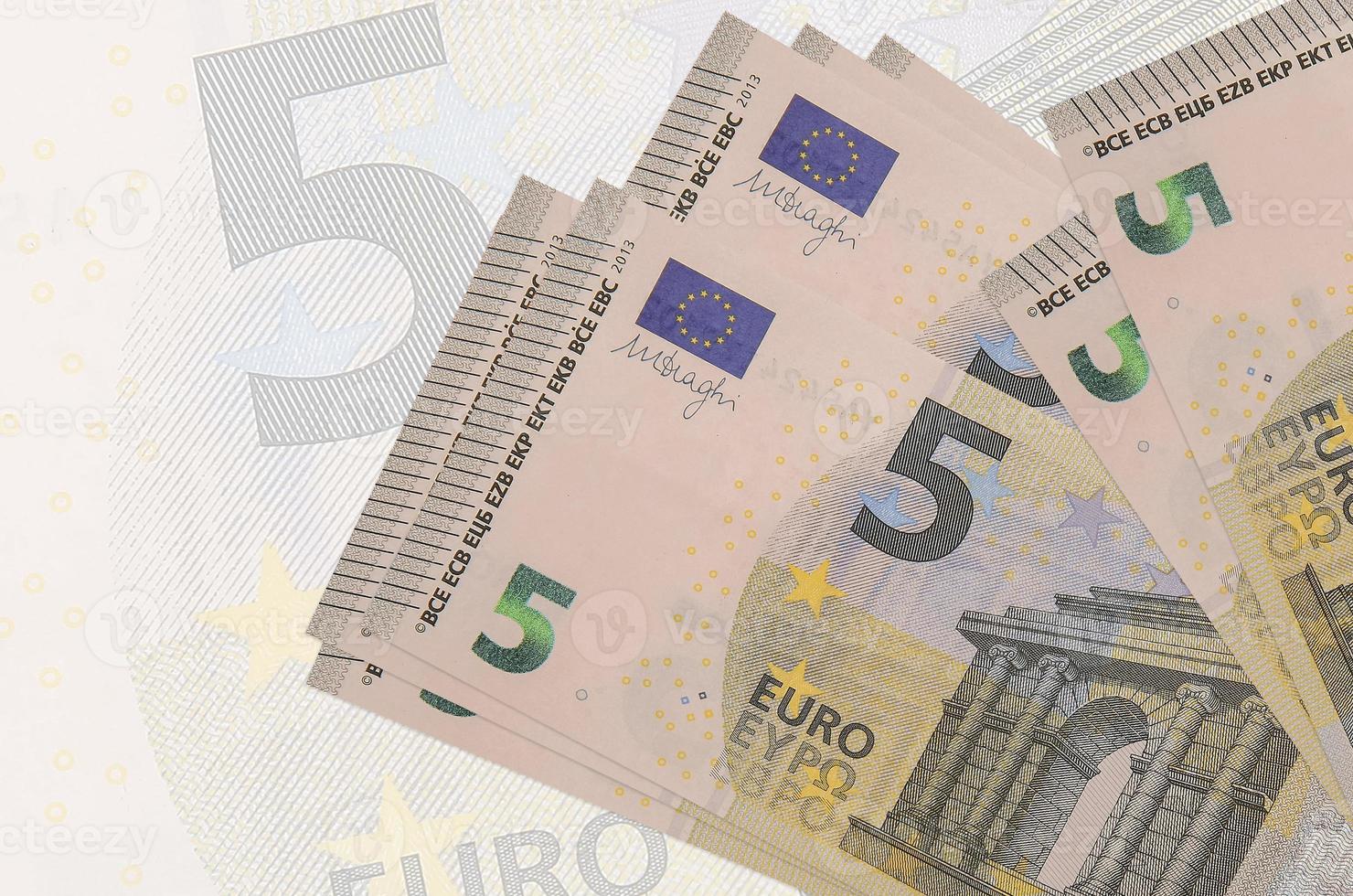 Los billetes de 5 euros se encuentran apilados sobre el fondo de un gran billete semitransparente. presentación abstracta de la moneda nacional foto