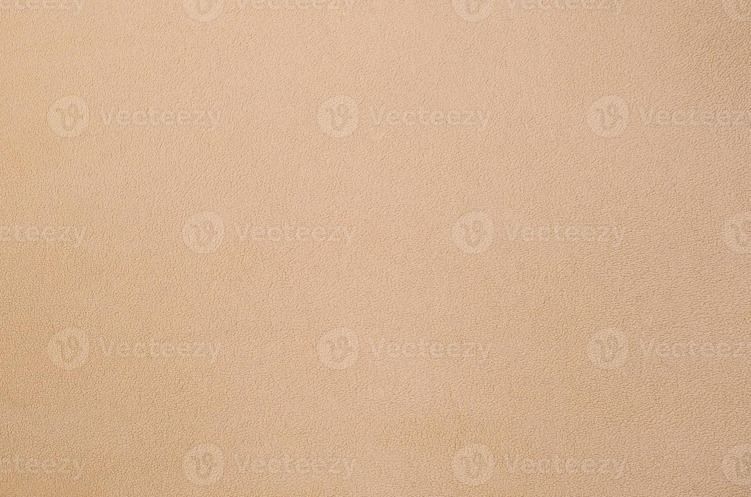 The blanket of furry orange fleece fabric. A background texture of light orange soft plush fleece material photo