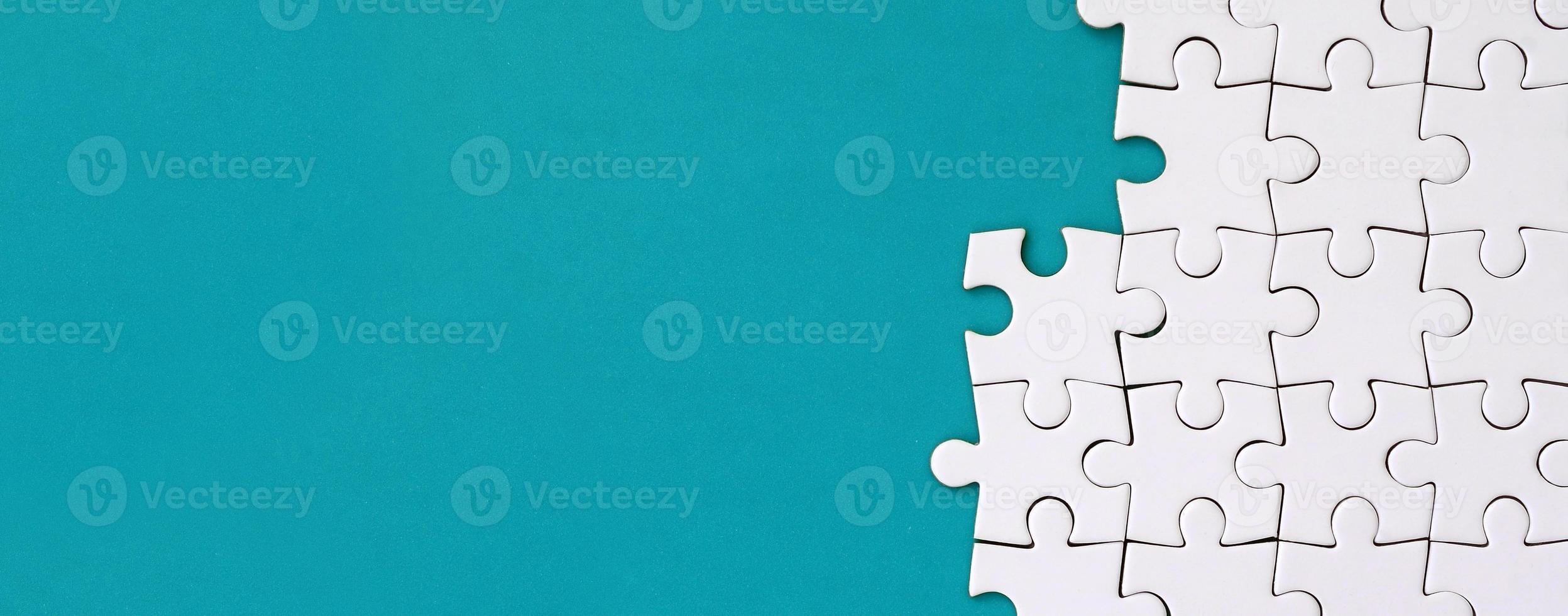 Fragment of a folded white jigsaw puzzle on the background of a blue plastic surface. Texture photo with copy space for text