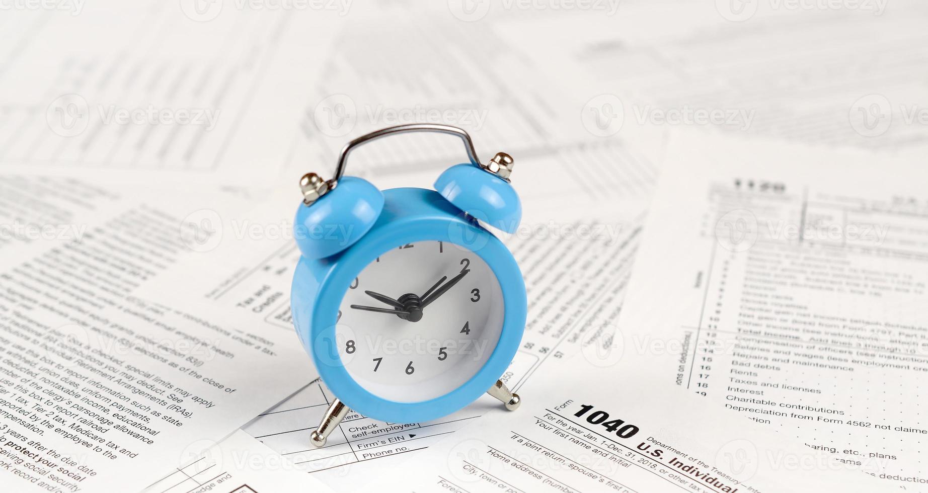 1040 Individual income tax return form and blue alarm clock photo