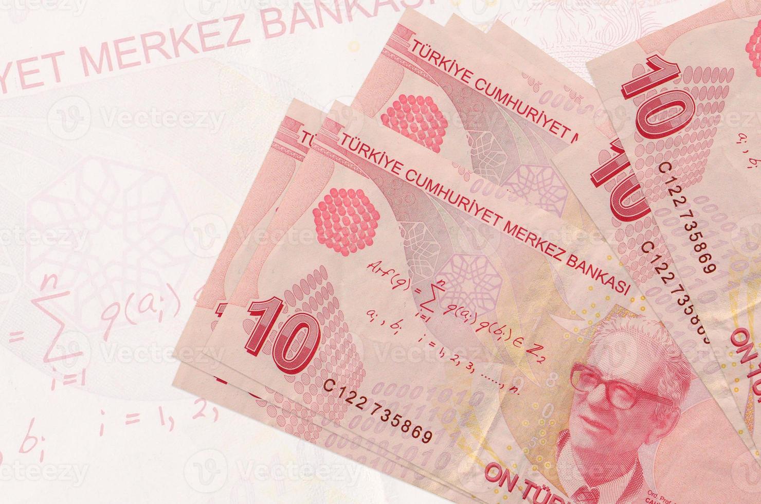 10 billetes de liras turcas se encuentran apilados sobre el fondo de un gran billete semitransparente. presentación abstracta de la moneda nacional foto