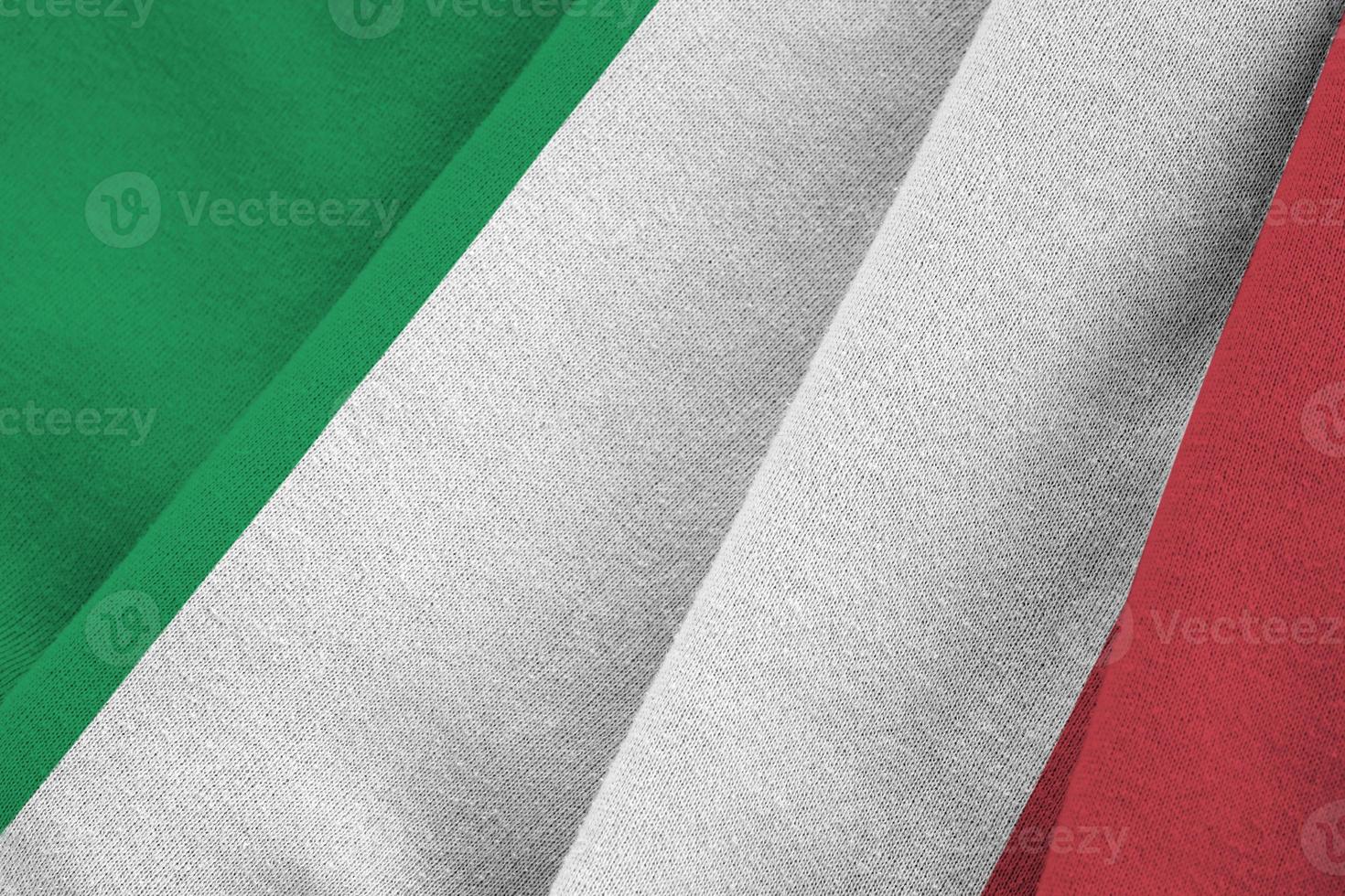 Italy flag with big folds waving close up under the studio light indoors. The official symbols and colors in banner photo