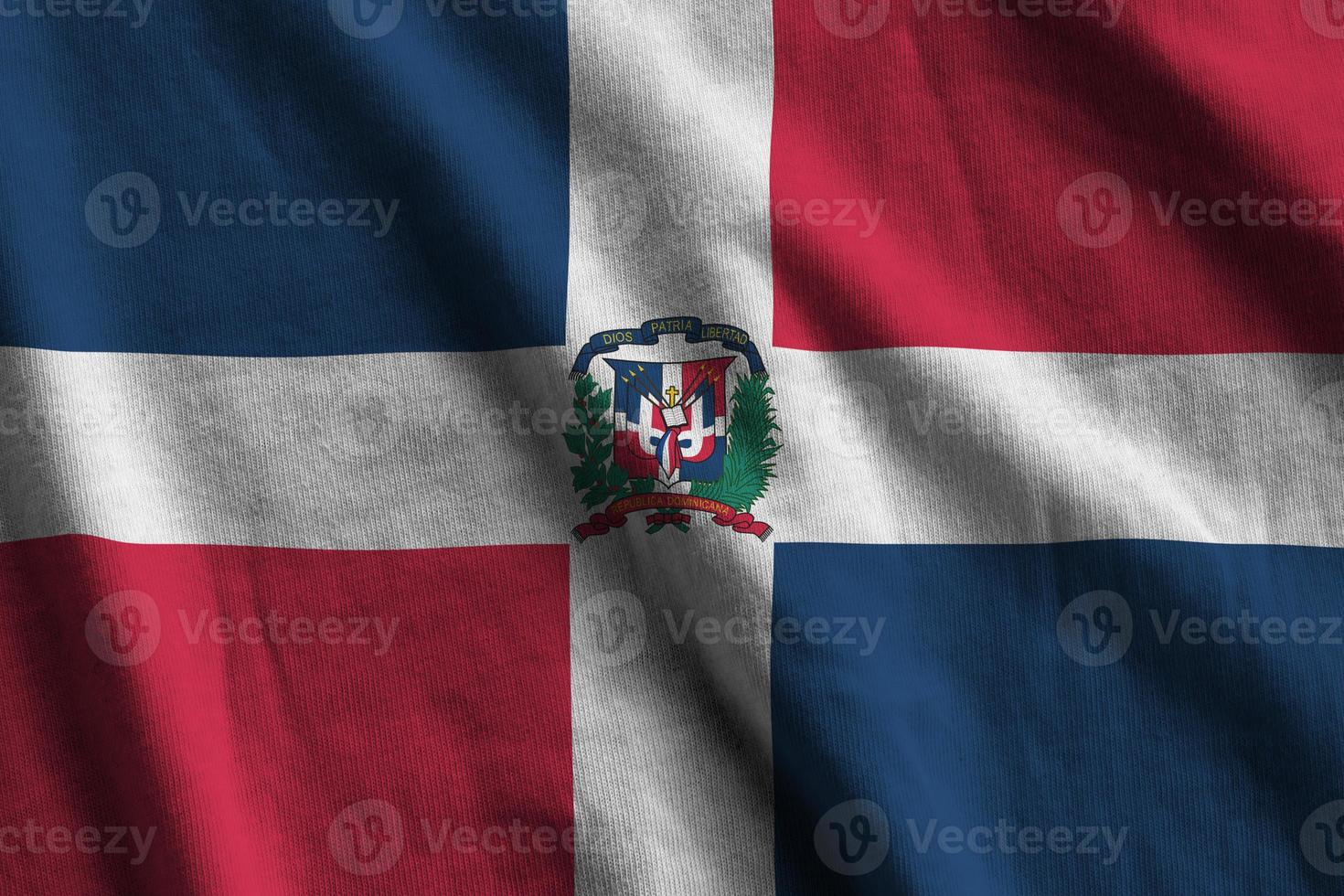 Dominican Republic flag with big folds waving close up under the studio light indoors. The official symbols and colors in banner photo