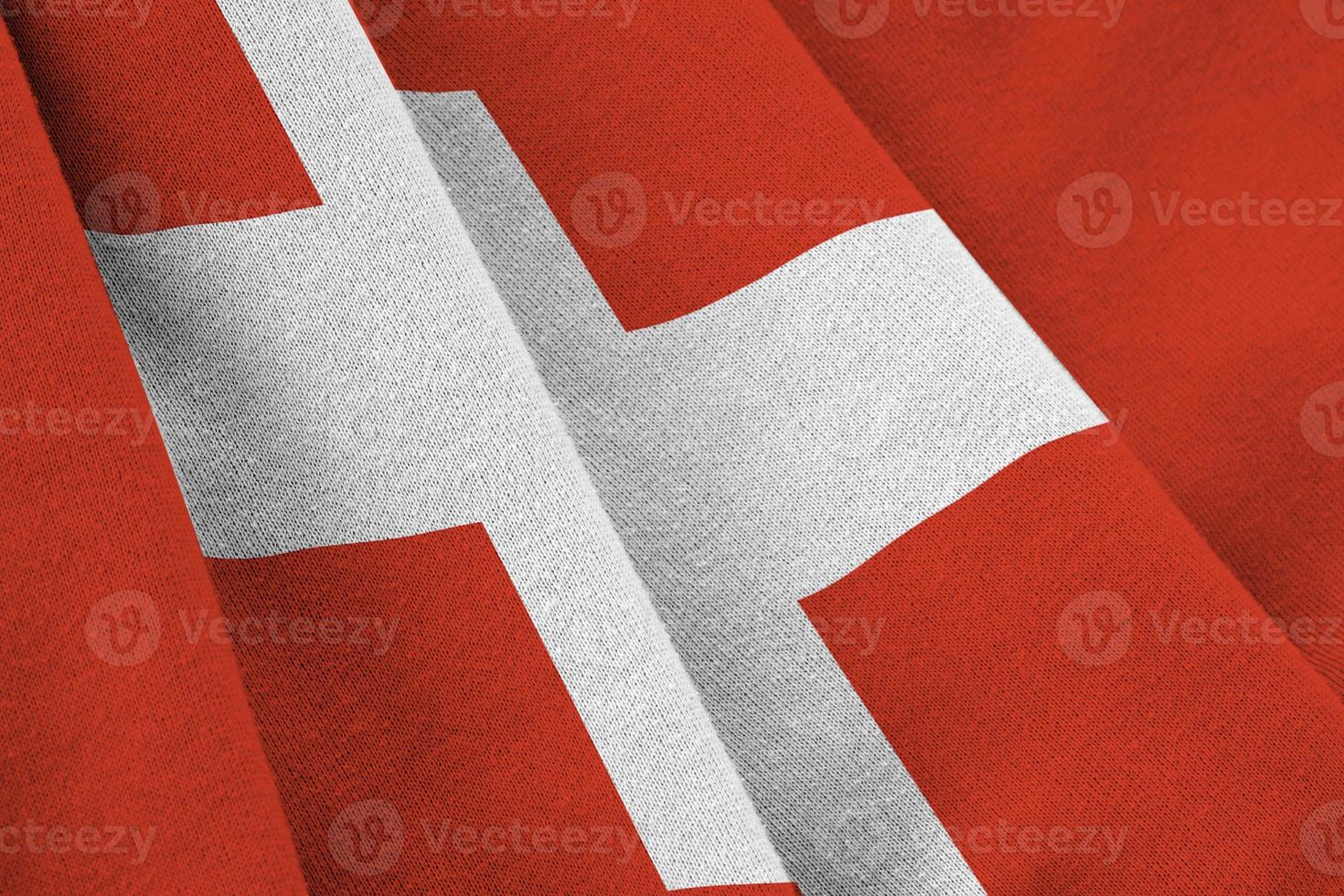 Switzerland flag with big folds waving close up under the studio light indoors. The official symbols and colors in banner photo