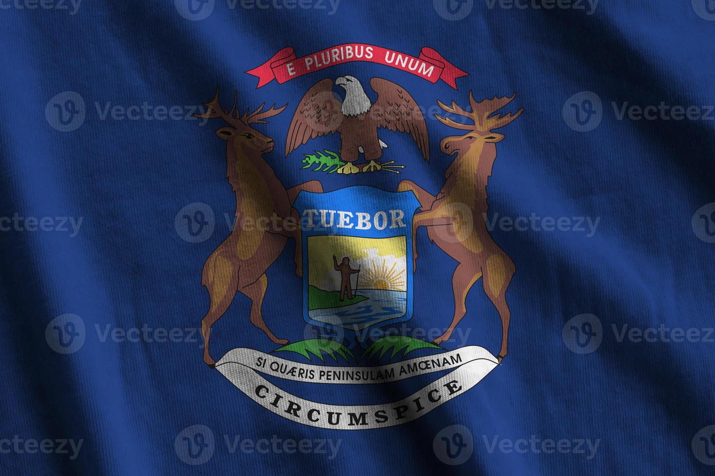 Michigan US state flag with big folds waving close up under the studio light indoors. The official symbols and colors in banner photo
