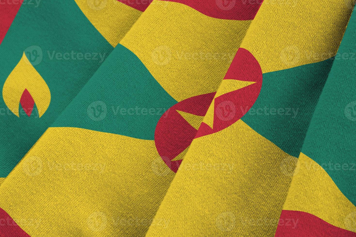 Grenada flag with big folds waving close up under the studio light indoors. The official symbols and colors in banner photo