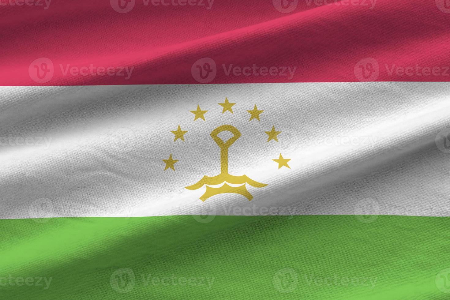 Tajikistan flag with big folds waving close up under the studio light indoors. The official symbols and colors in banner photo