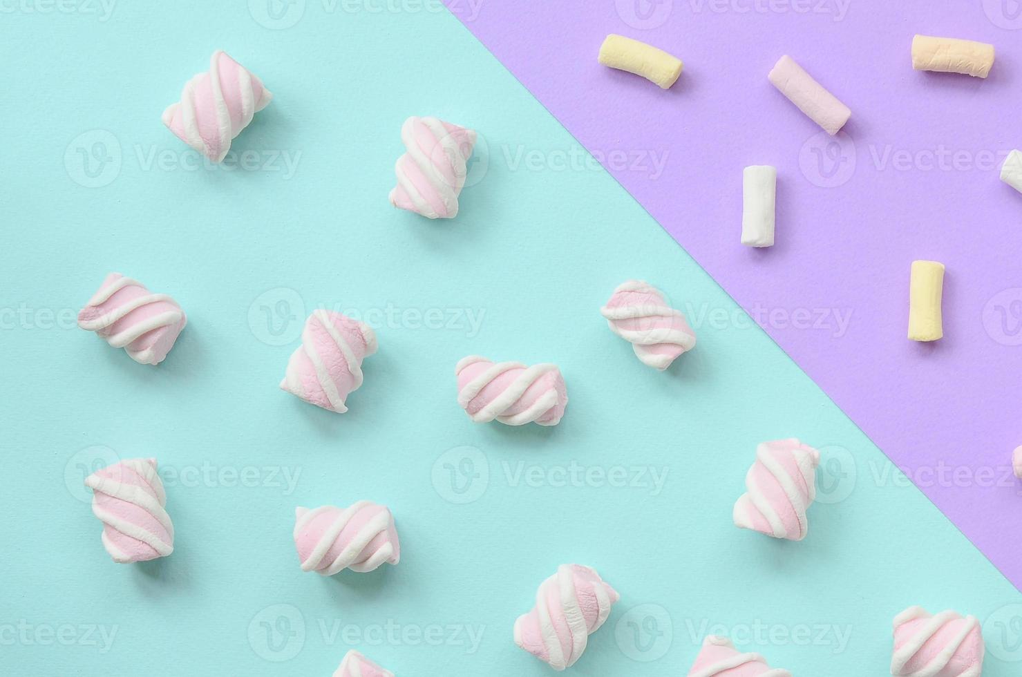 Colorful marshmallow laid out on violet and blue paper background. pastel creative textured pattern. minimal photo