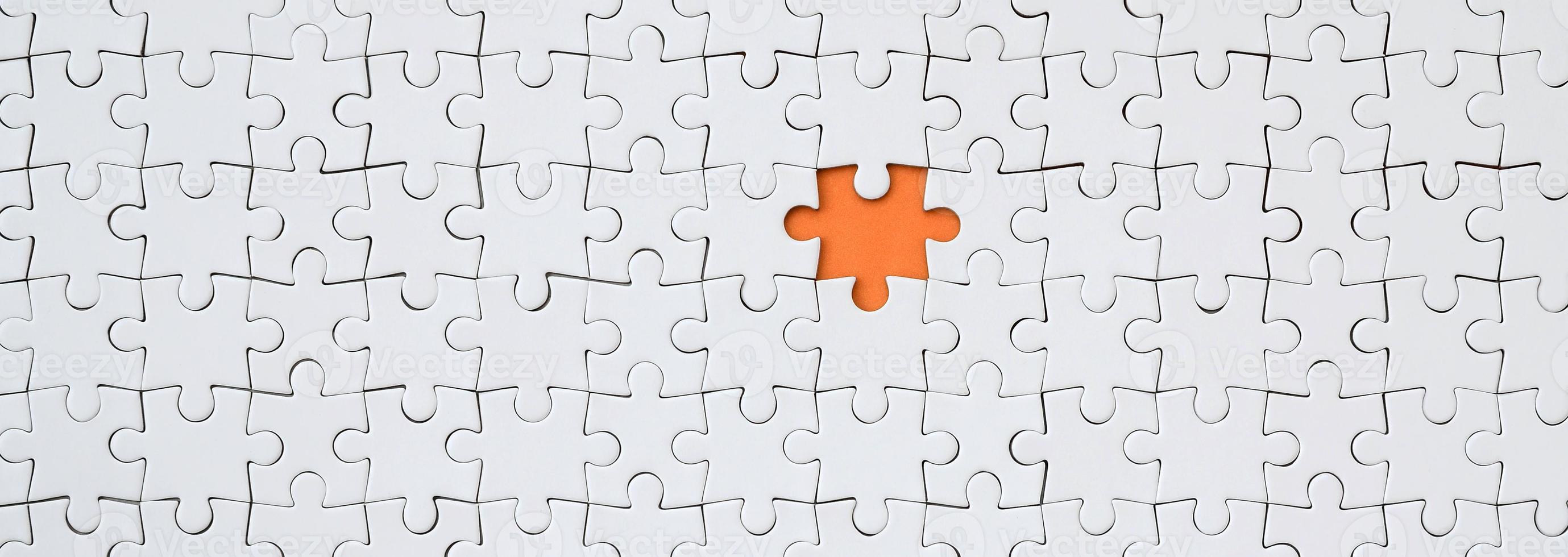 The texture of a white jigsaw puzzle in an assembled state with one missing element forming an orange space photo