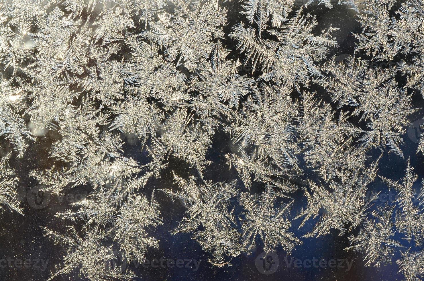 Snowflakes frost rime macro on window glass pane photo