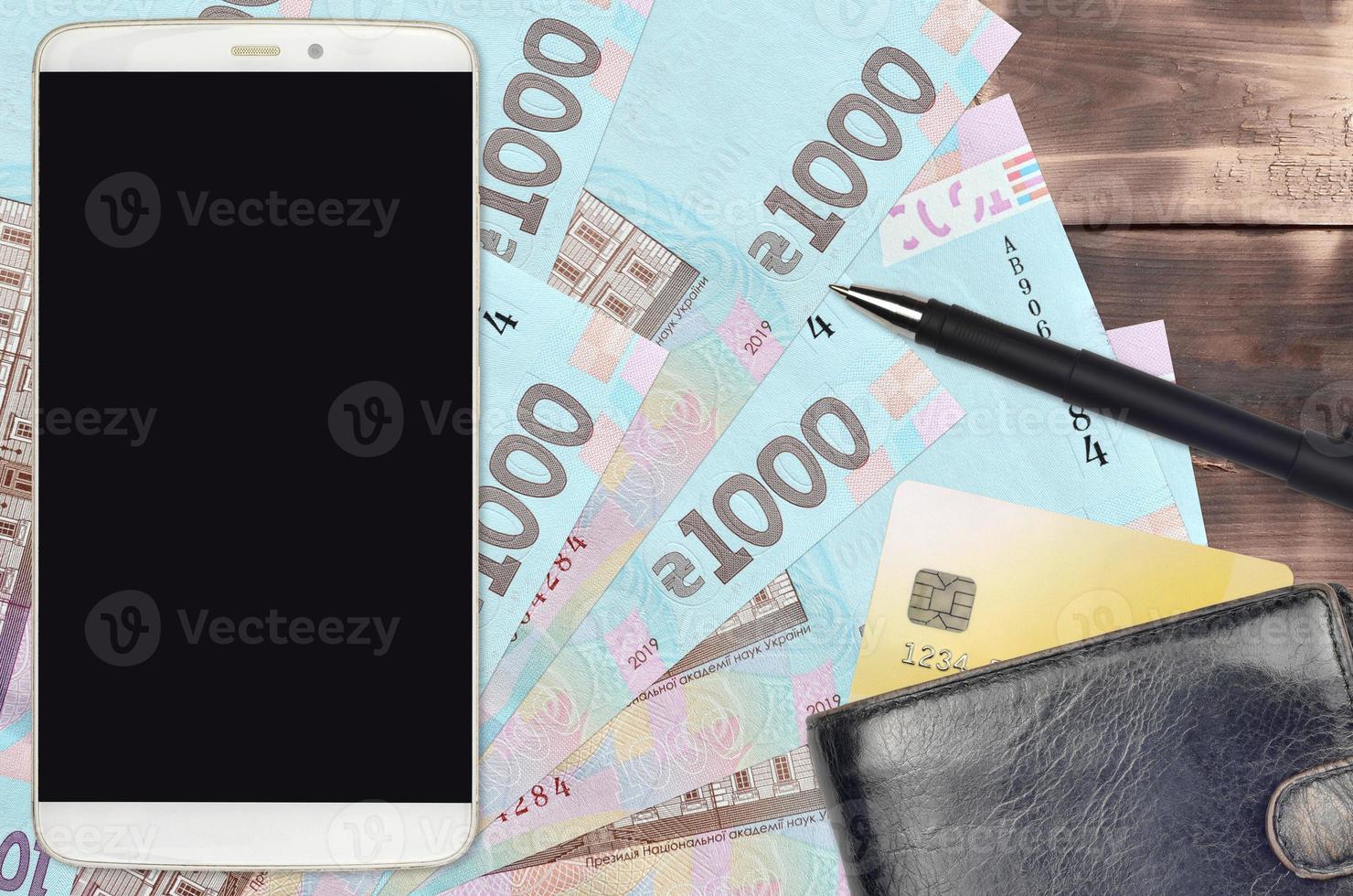 1000 Ukrainian hryvnias bills and smartphone with purse and credit card. E-payments or e-commerce concept. Online shopping and business with portable devices photo