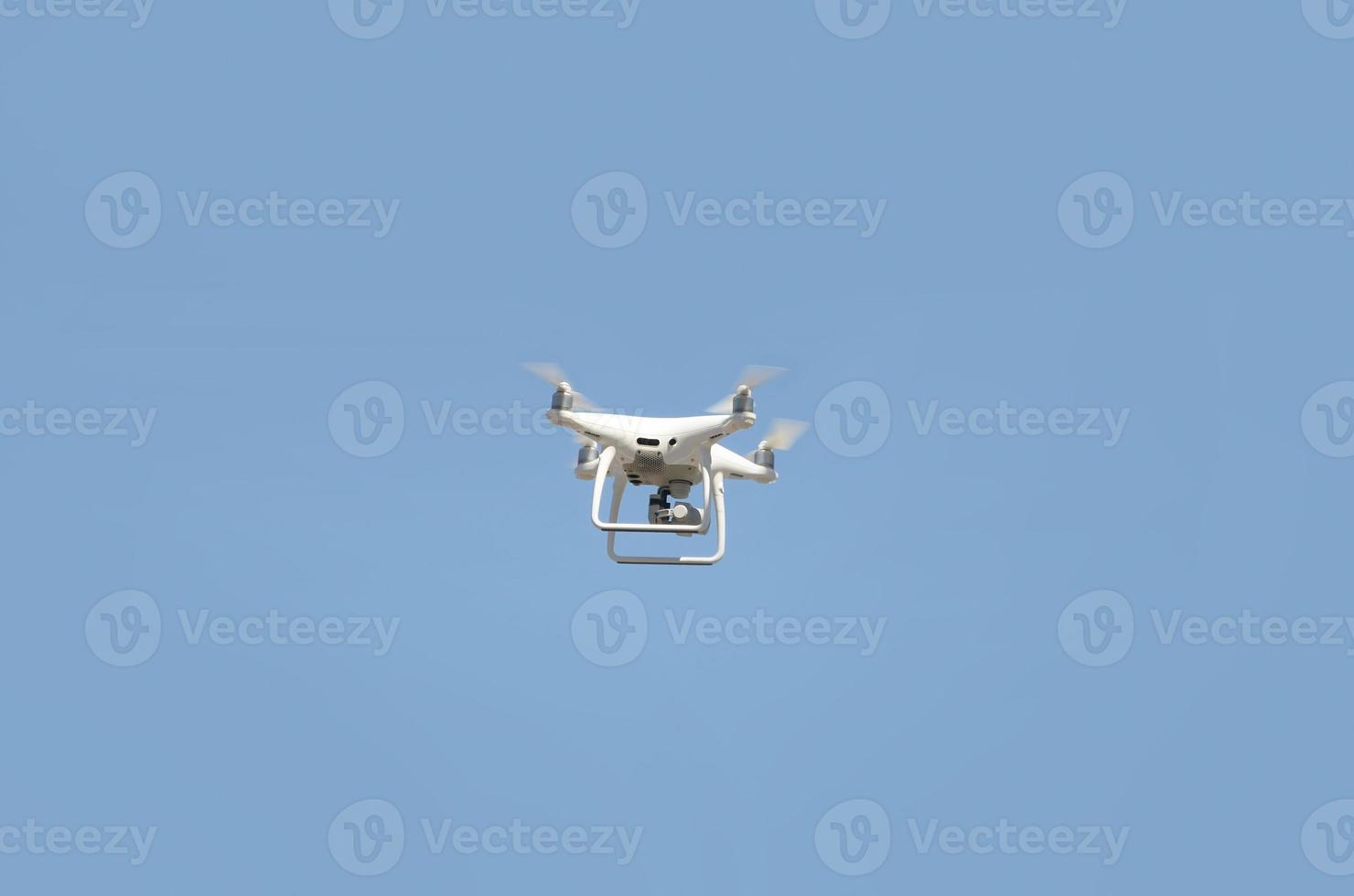 Big white drone hovering in a bright cloudless blue sky photo
