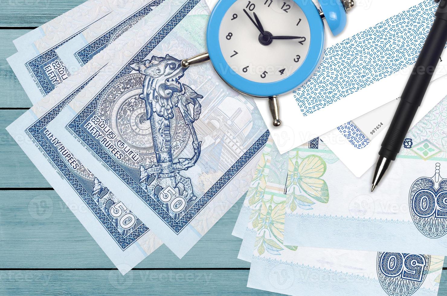 50 Sri Lankan rupees bills and alarm clock with pen and envelopes. Tax
