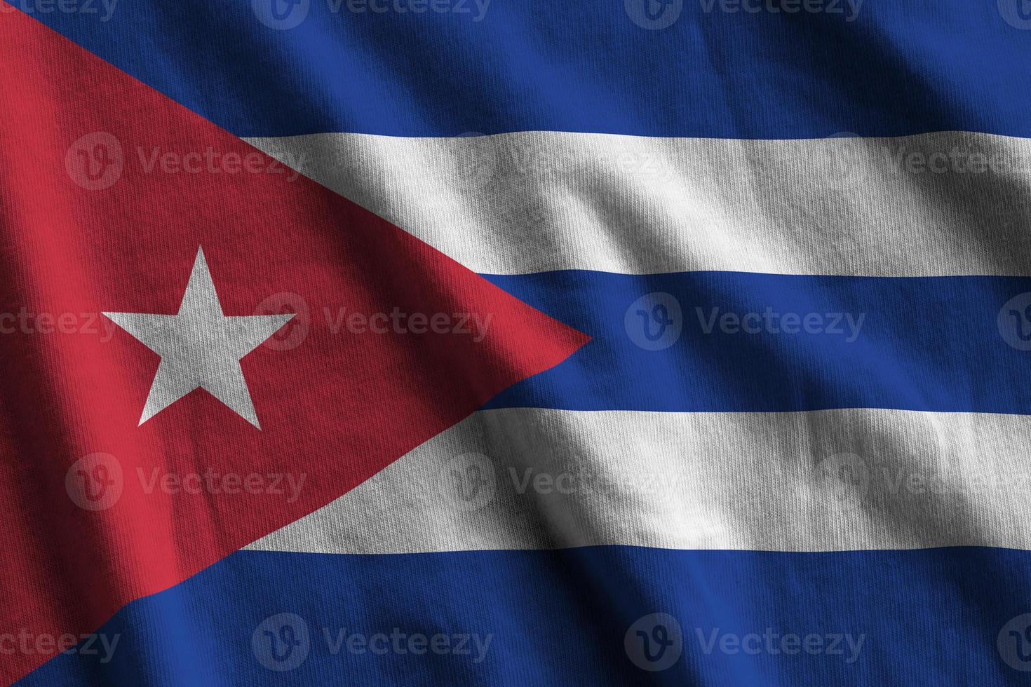 Cuba flag with big folds waving close up under the studio light indoors. The official symbols and colors in banner photo