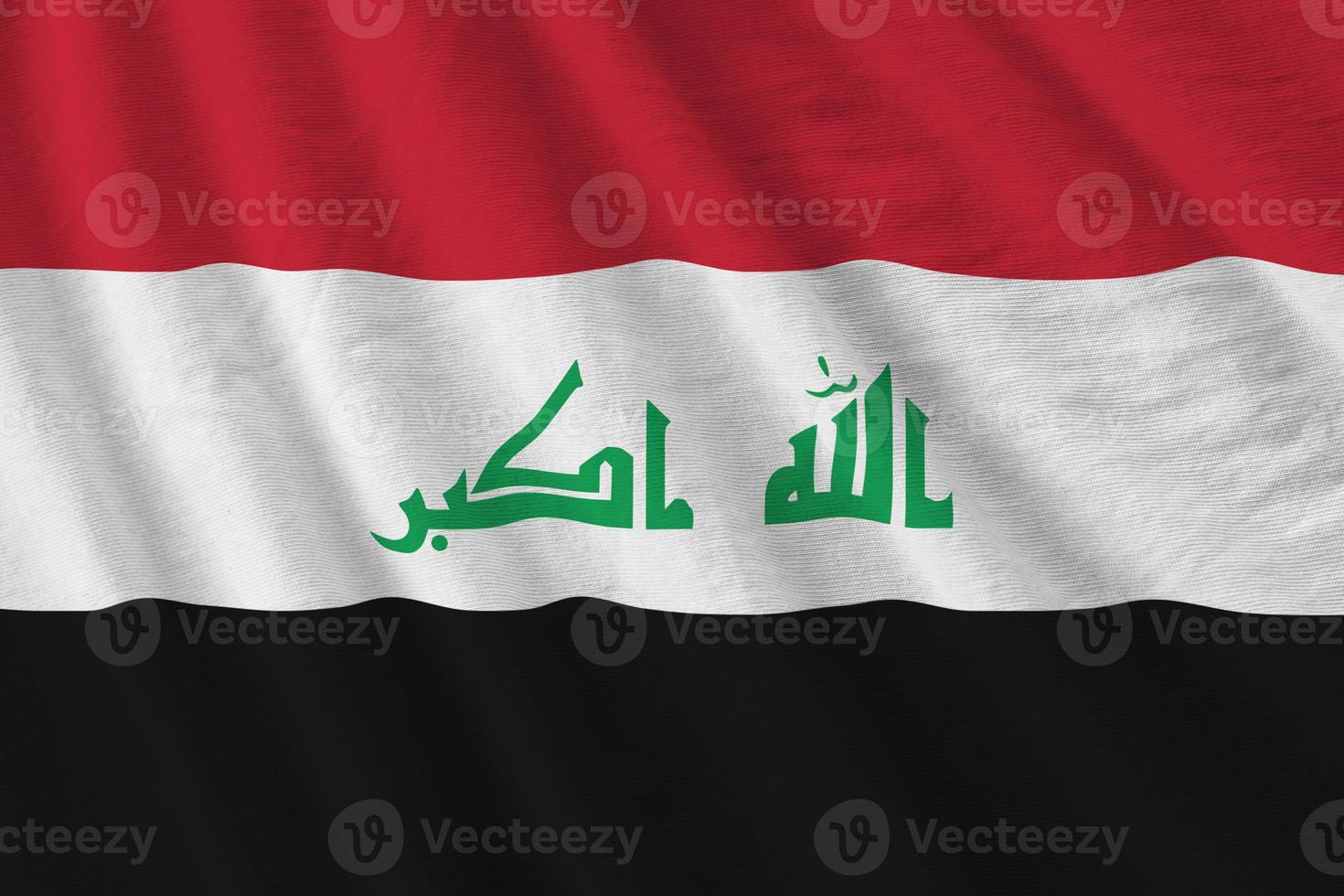 Iraq flag with big folds waving close up under the studio light indoors. The official symbols and colors in banner photo
