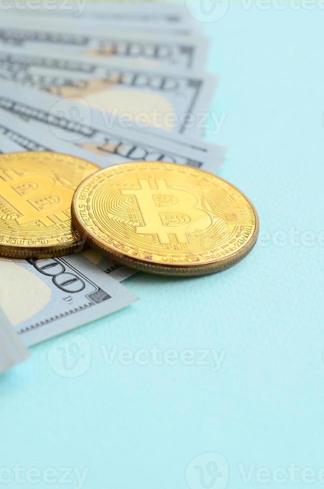 bitcoins dorados y billetes de cien dólares se encuentran en un fondo azul claro foto