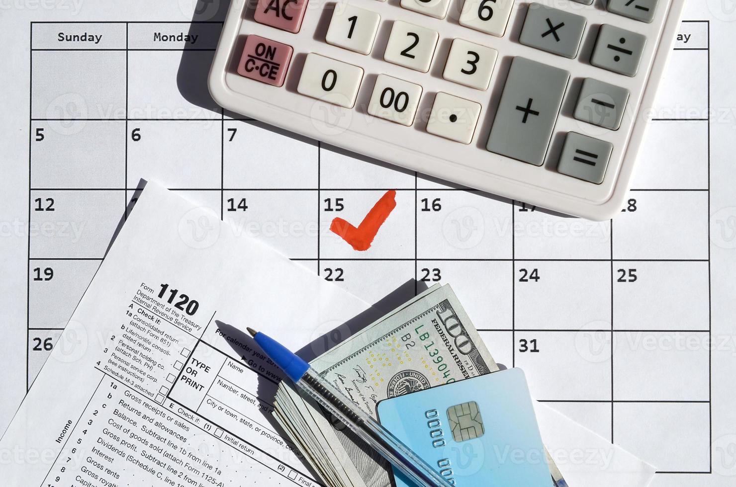 1120 Corporation Income Tax Return blank with dollar bills, calculator and pen on calendar page with marked 15th April photo