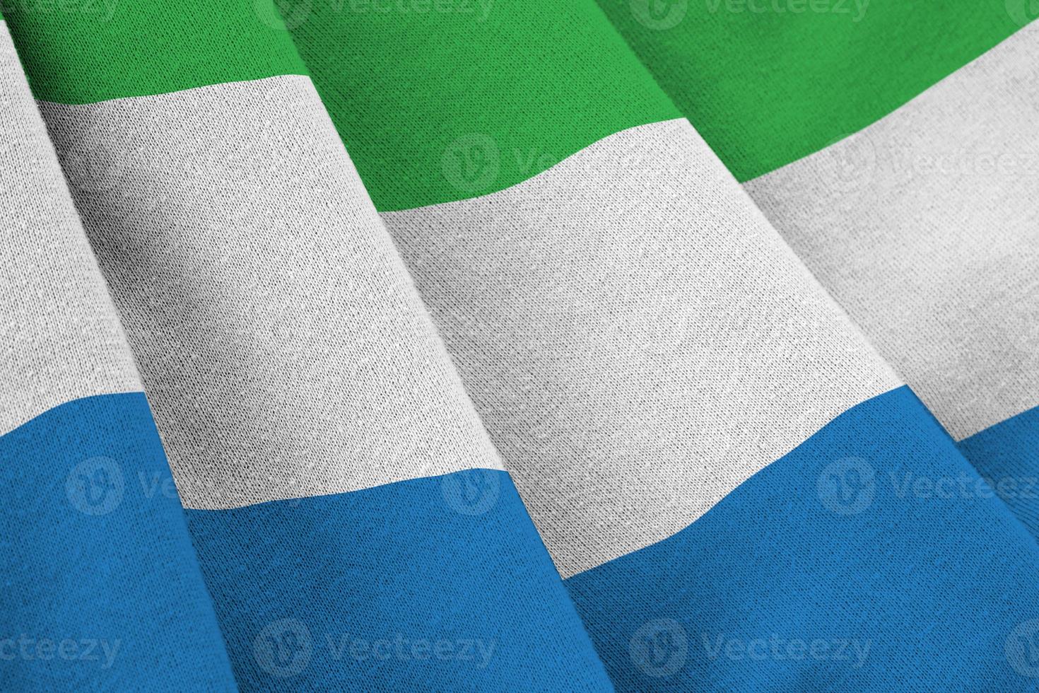 Sierra Leone flag with big folds waving close up under the studio light indoors. The official symbols and colors in banner photo