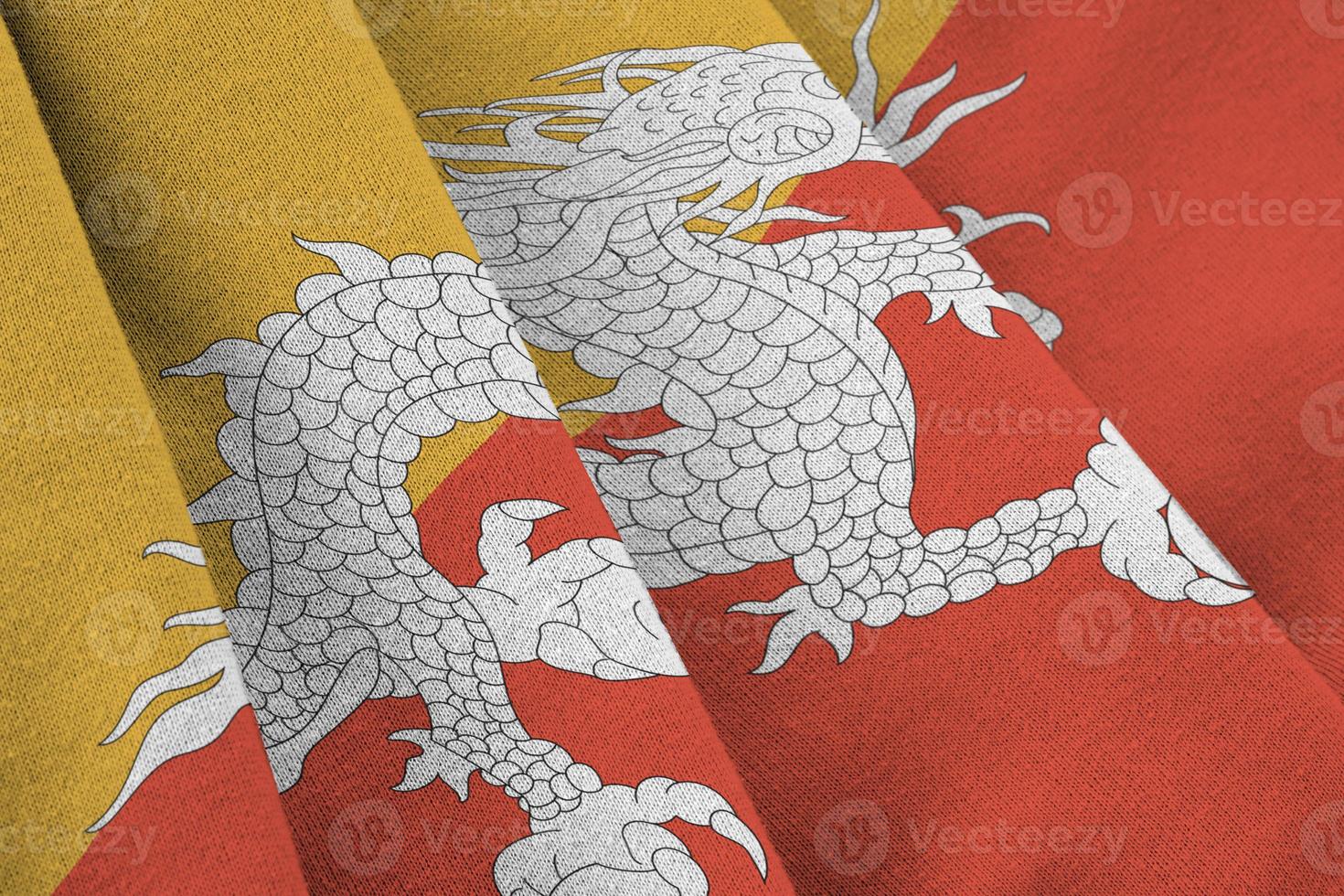Bhutan flag with big folds waving close up under the studio light indoors. The official symbols and colors in banner photo