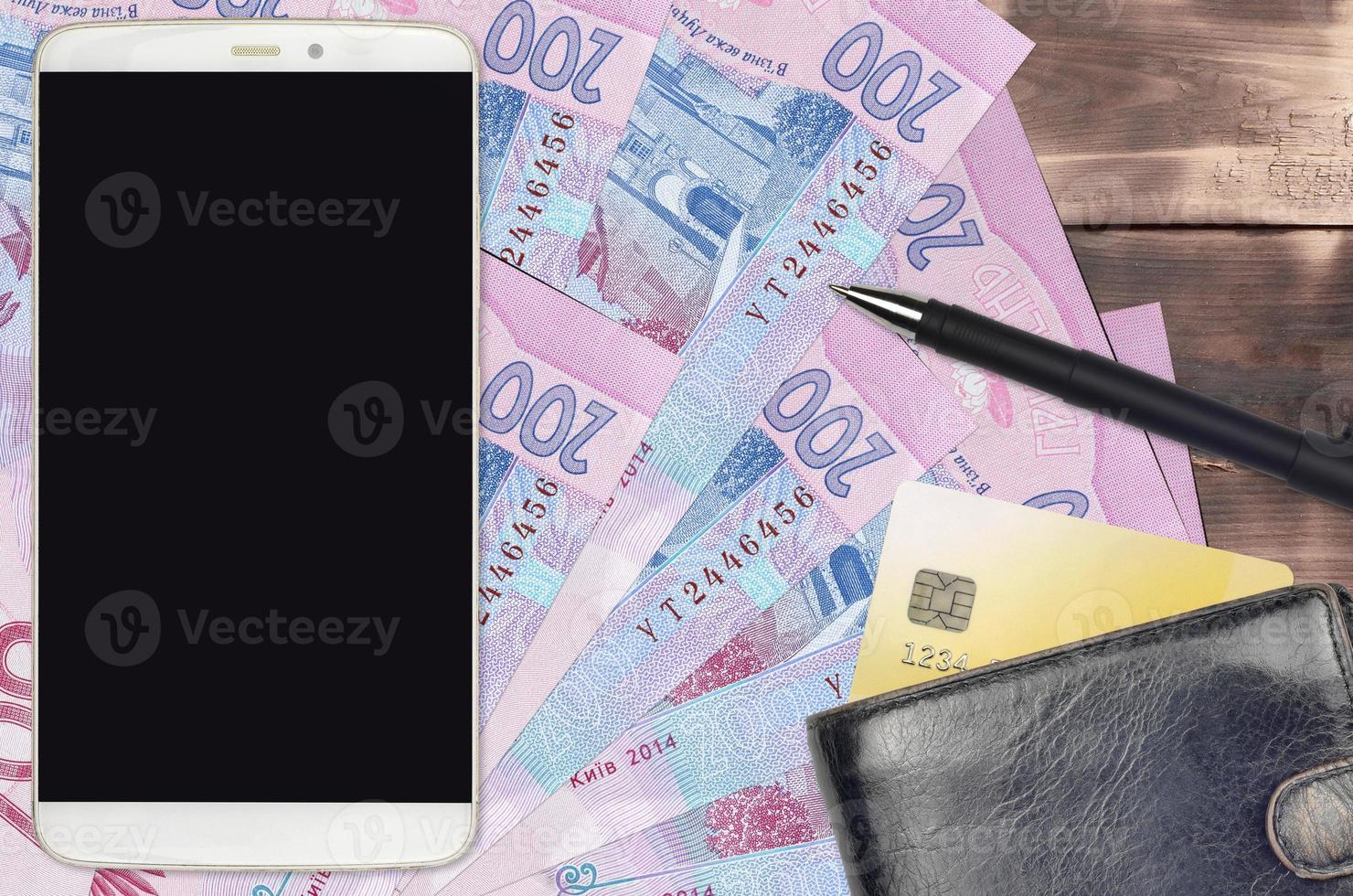 200 Ukrainian hryvnias bills and smartphone with purse and credit card. E-payments or e-commerce concept. Online shopping and business with portable devices photo