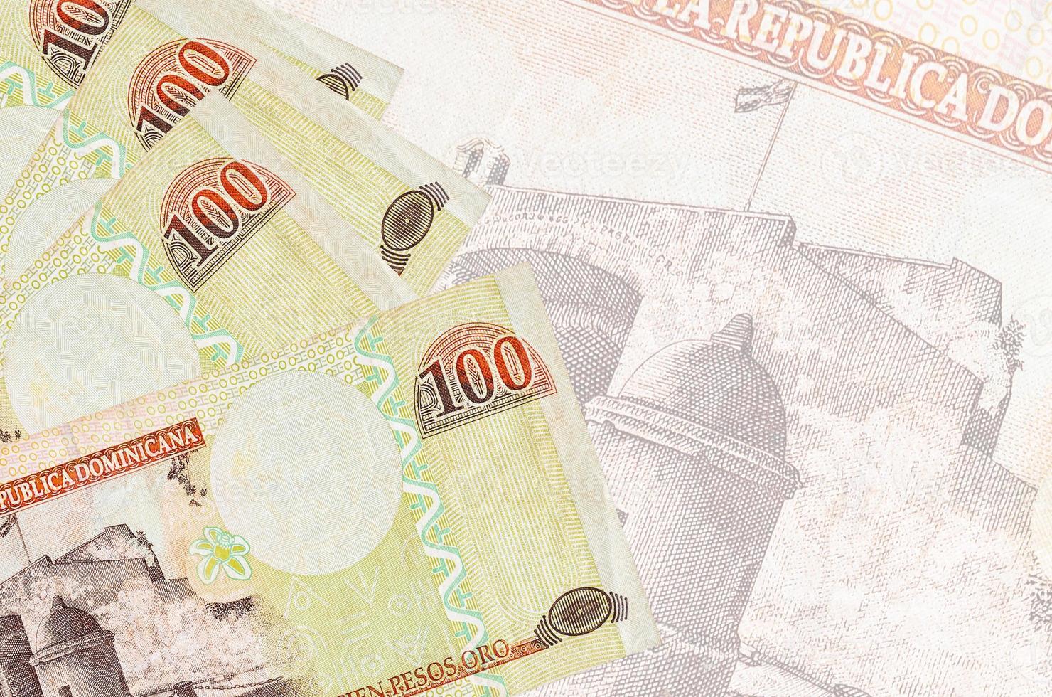 Los billetes de 100 pesos dominicanos se encuentran apilados sobre el fondo de un gran billete semitransparente. fondo de negocios abstracto foto