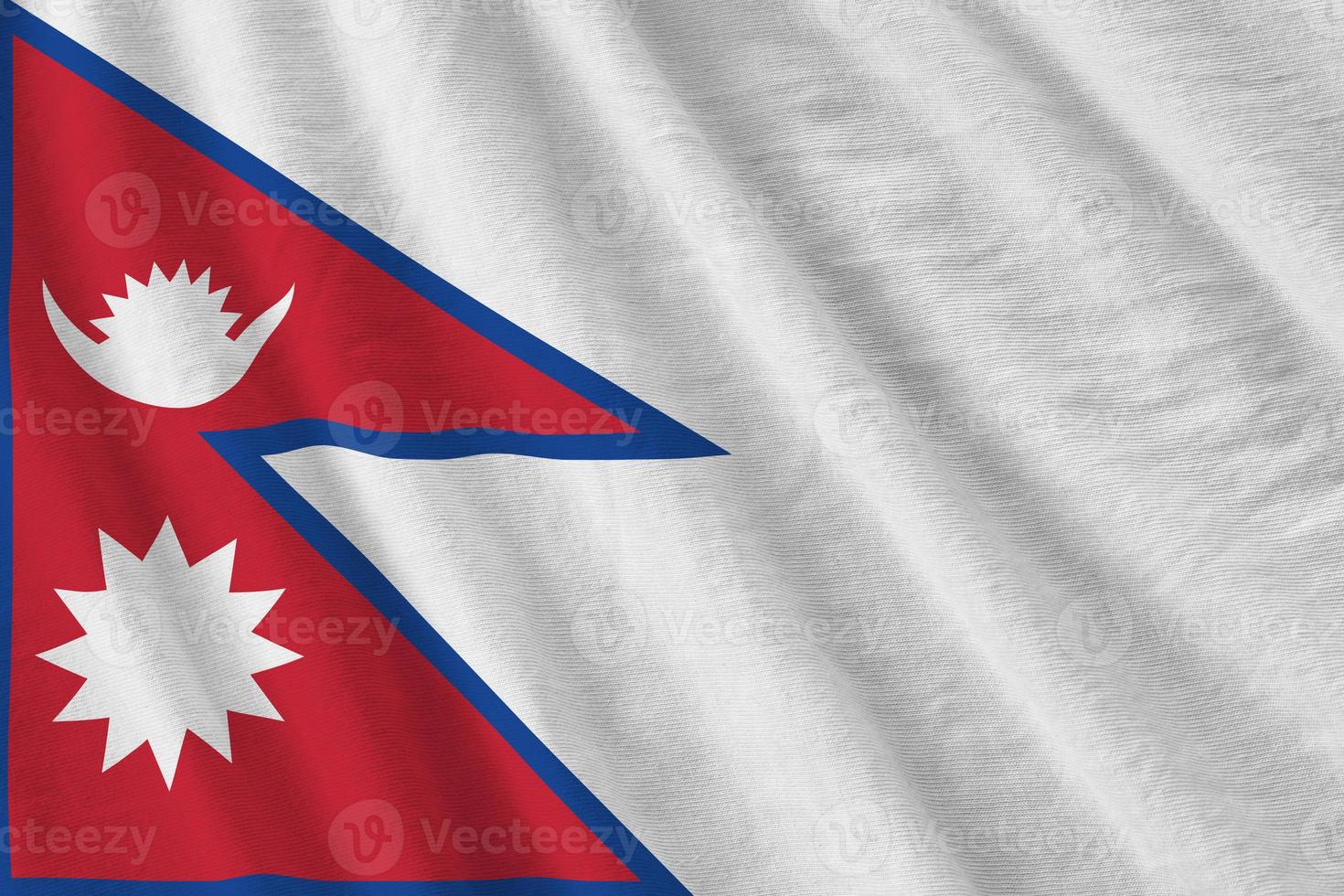 Nepal flag with big folds waving close up under the studio light indoors. The official symbols and colors in banner photo