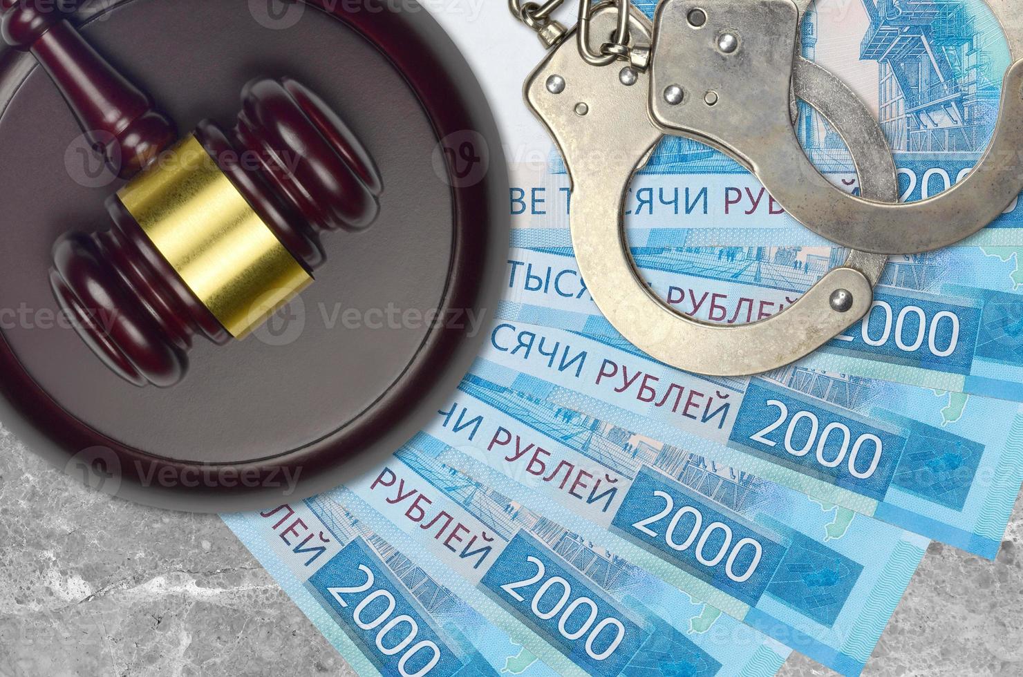 2000 russian rubles bills and judge hammer with police handcuffs on court desk. Concept of judicial trial or bribery. Tax avoidance photo