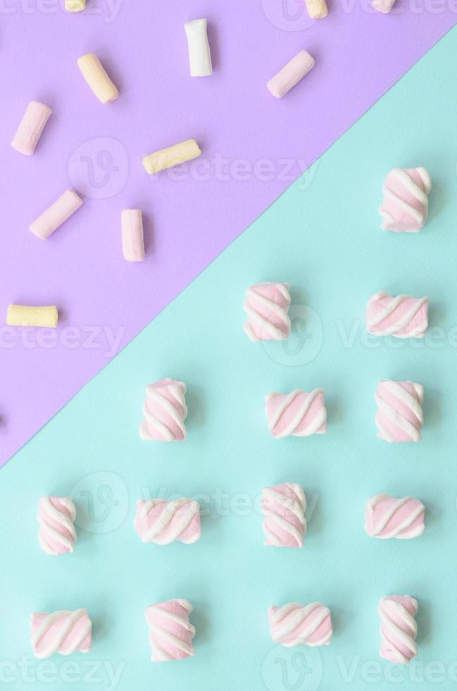 Colorful marshmallow laid out on violet and blue paper background. pastel creative textured pattern. minimal photo