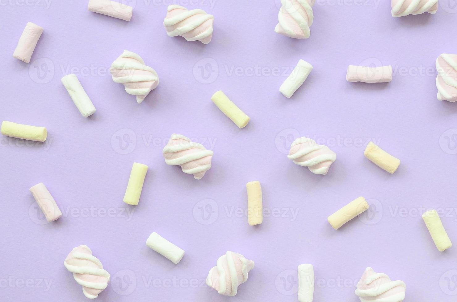 Colorful marshmallow laid out on violet paper background. pastel creative texture. minimal photo