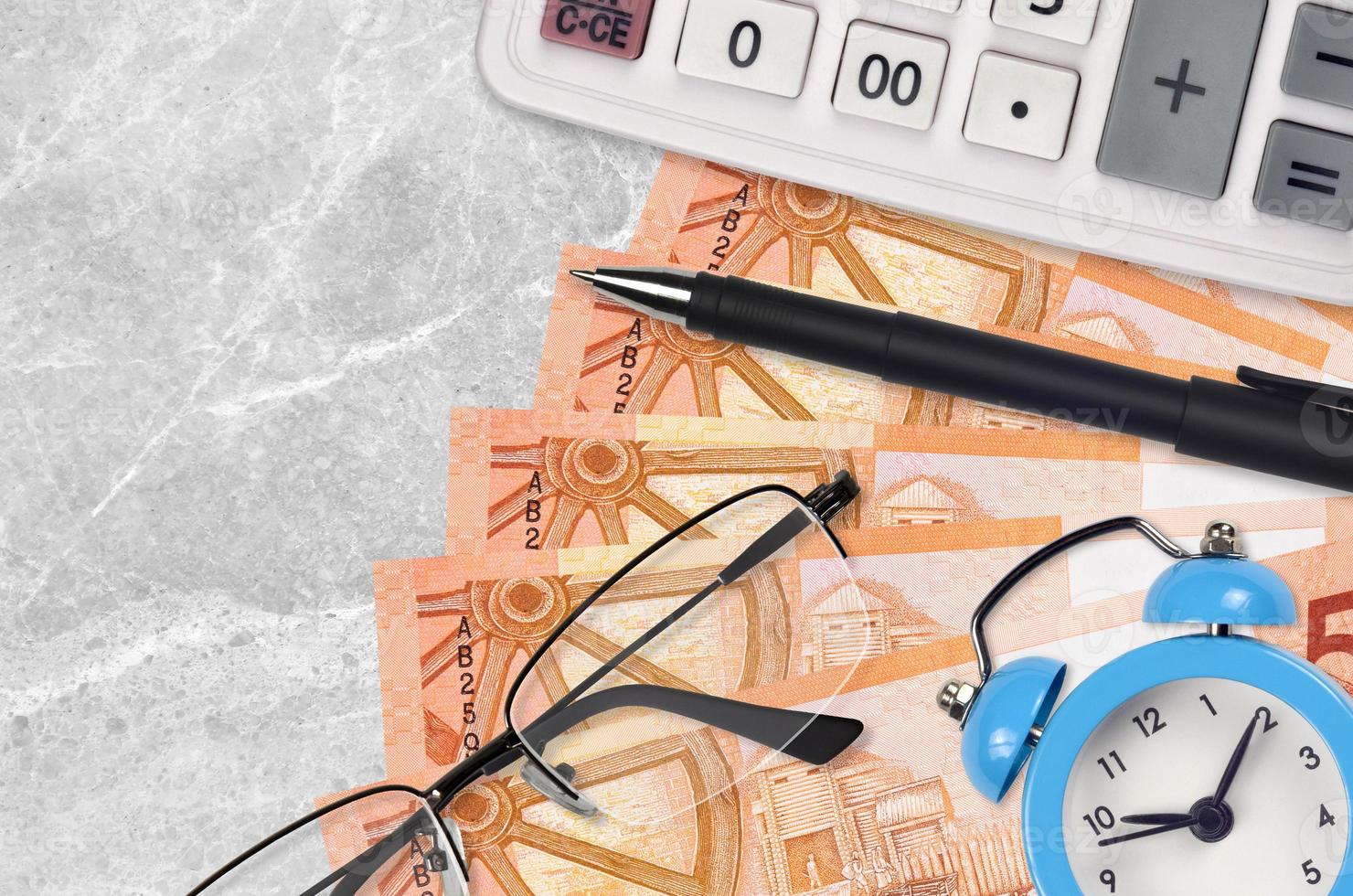 5 Belorussian rubles bills and calculator with glasses and pen. Business loan or tax payment season concept. Time to pay taxes photo