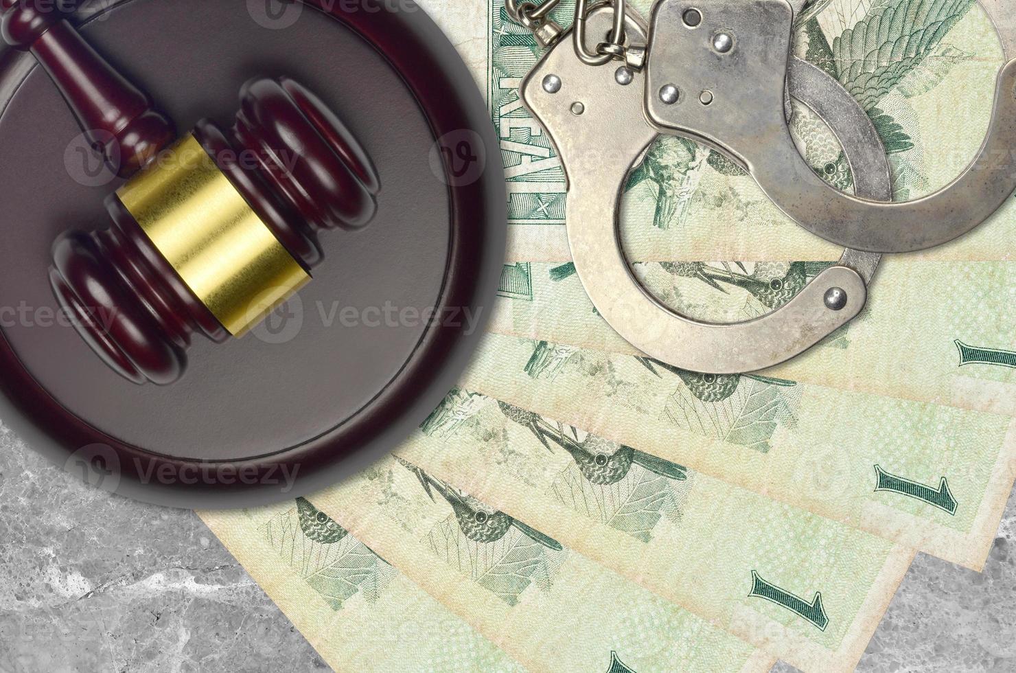 1 Brazilian real bills and judge hammer with police handcuffs on court desk. Concept of judicial trial or bribery. Tax avoidance photo