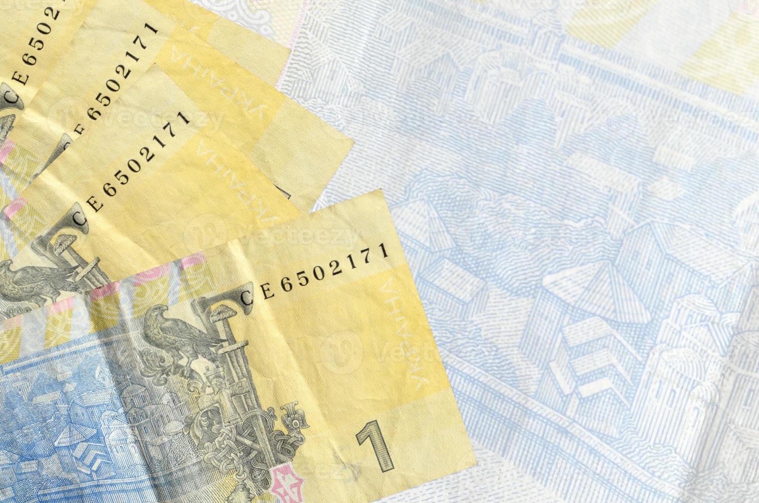 1 Ukrainian hryvnia bills lies in stack on background of big semi-transparent banknote. Abstract business background photo