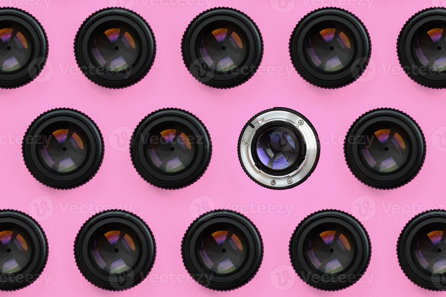 A few camera lenses with a closed aperture lie on texture background of fashion pastel pink color paper in minimal concept. Abstract trendy pattern photo