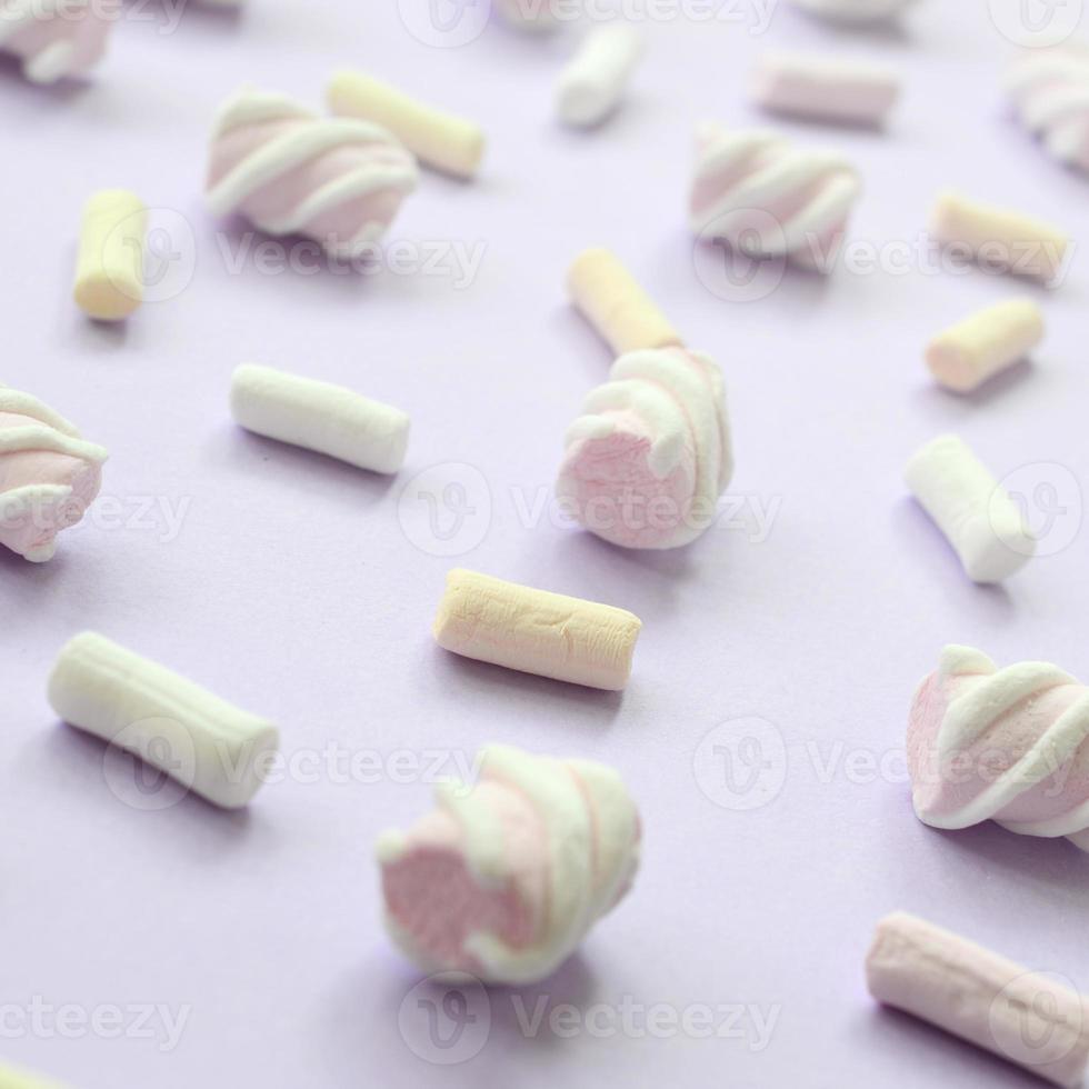 Colorful marshmallow laid out on violet paper background. pastel creative textured pattern. Perspective macro shot photo