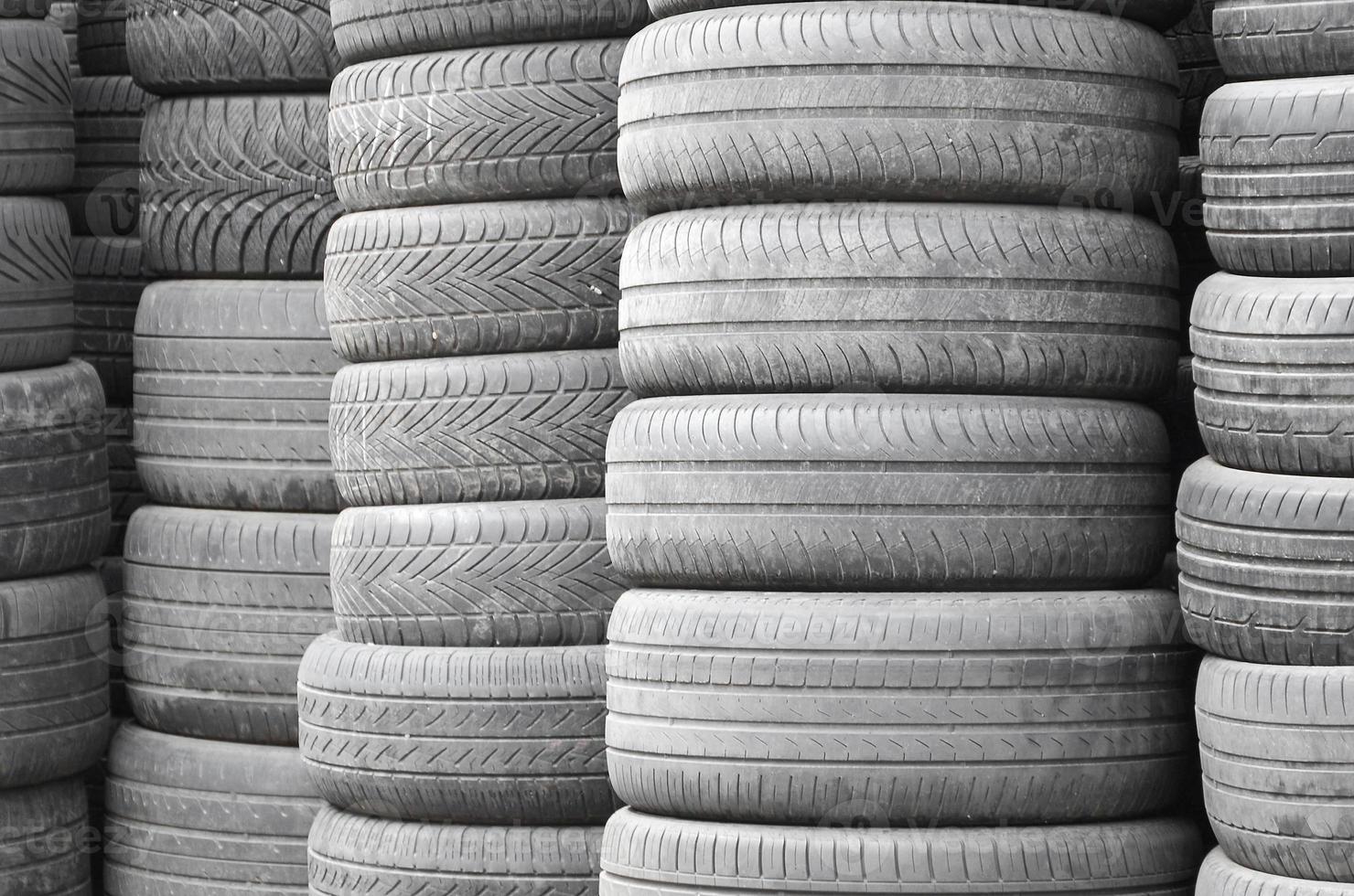 Old used tires stacked with high piles in secondary car parts shop garage photo