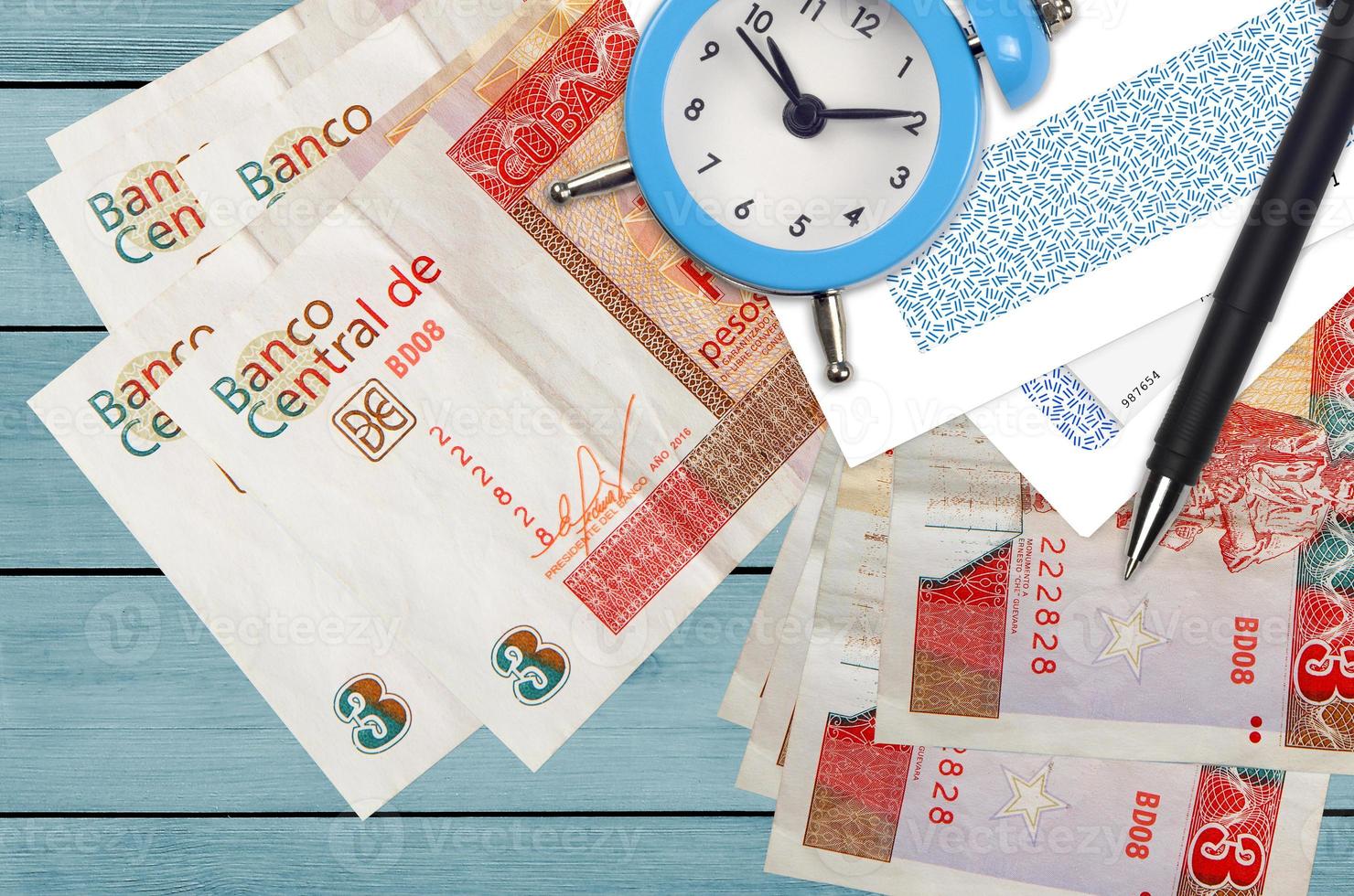 3 cuban pesos convertibles bills and alarm clock with pen and envelopes. Tax season concept, payment deadline for credit or loan. Financial operations using postal service photo