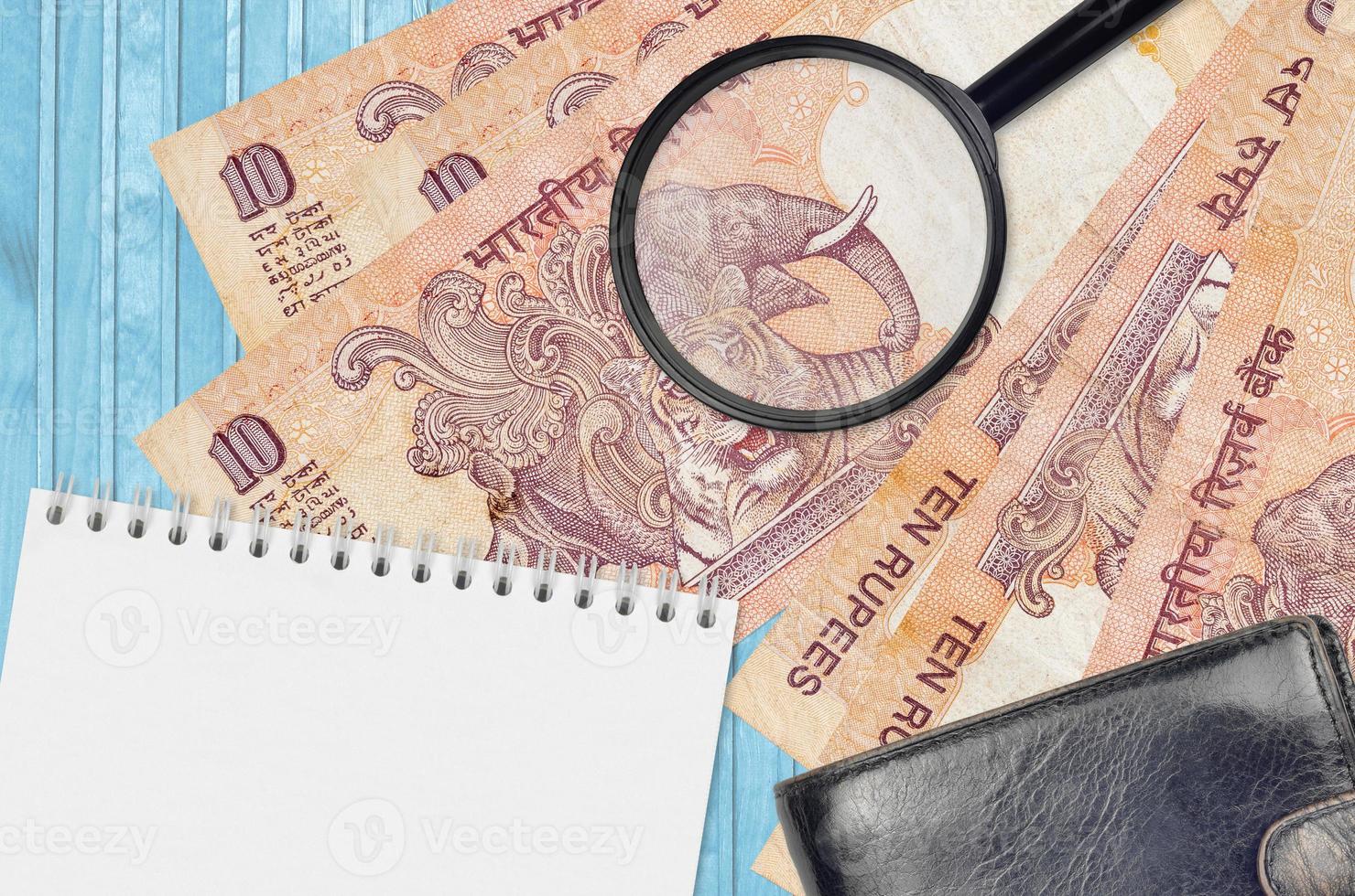 10 Indian rupees bills and magnifying glass with black purse and notepad. Concept of counterfeit money. Search for differences in details on money bills to detect fake photo