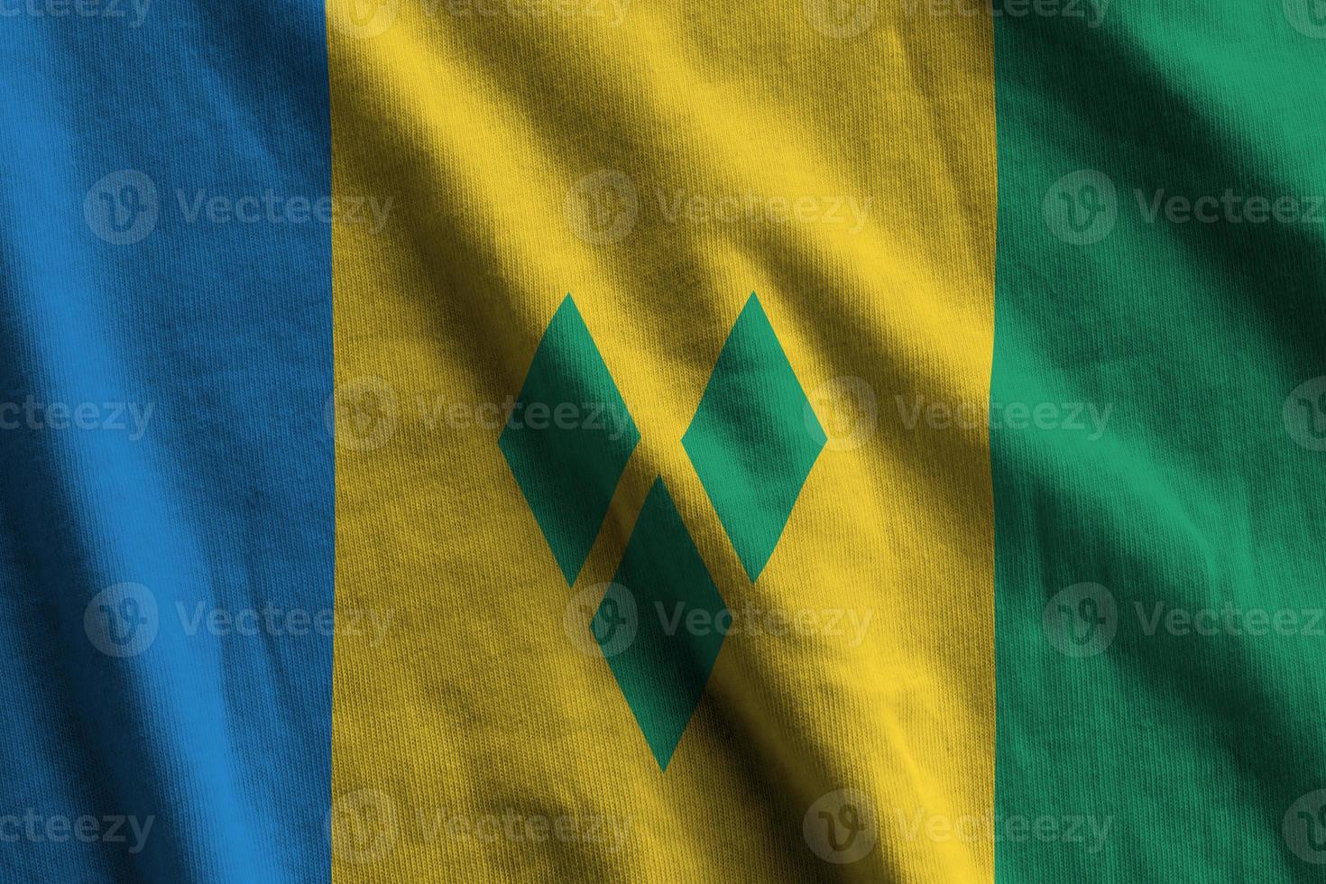 Saint Vincent and the Grenadines flag with big folds waving close up under the studio light indoors. The official symbols and colors in banner photo