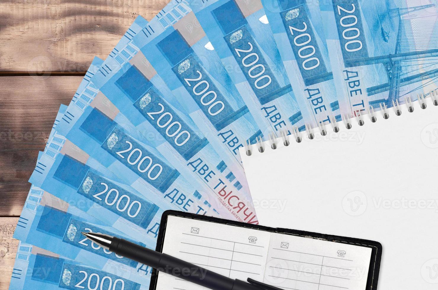 2000 russian rubles bills fan and notepad with contact book and black pen. Concept of financial planning and business strategy photo
