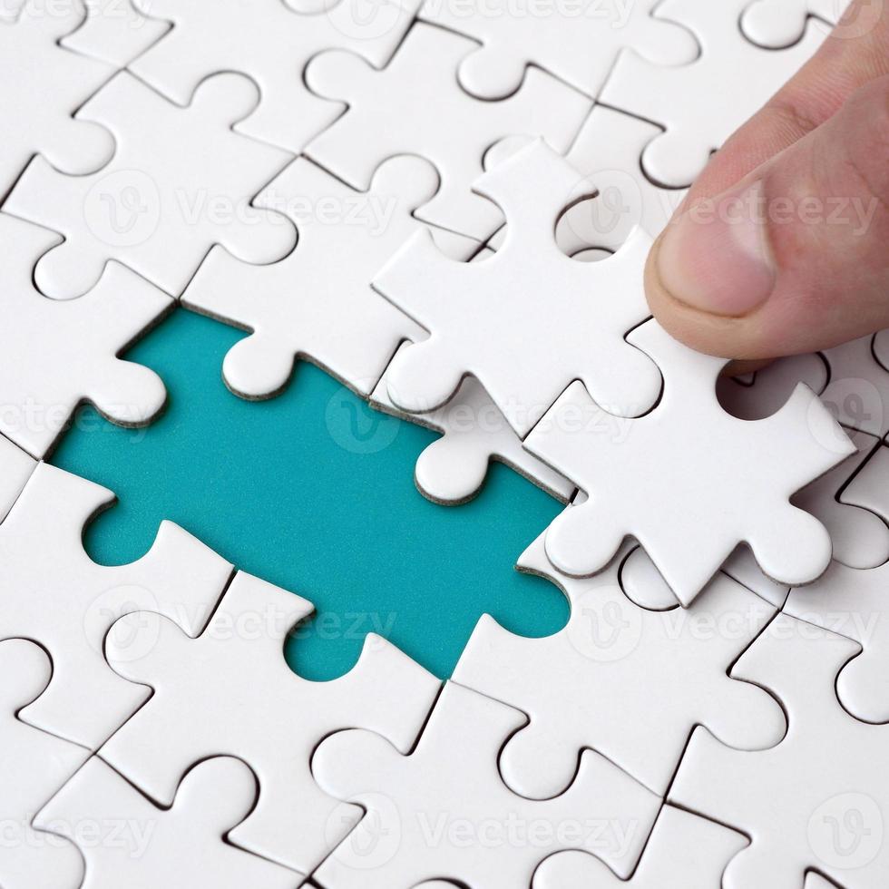 The human hand fills the last missing elements of the surface from the jigsaw puzzle. The concept of the completion of the initiated cases photo